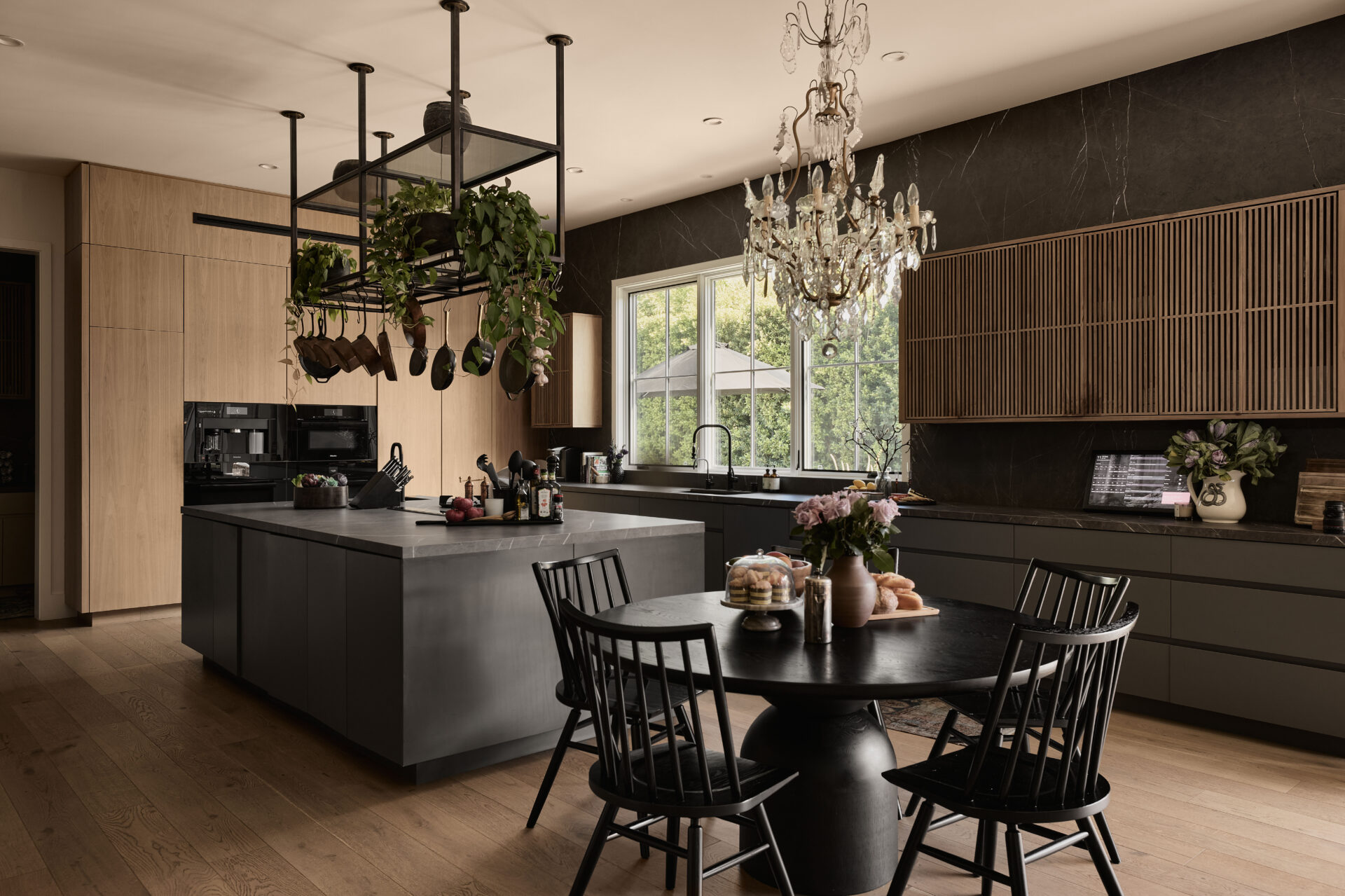 Kitchen with matte black cabinetry, stone surfaces, and natural light filtering in through the window above the sink.