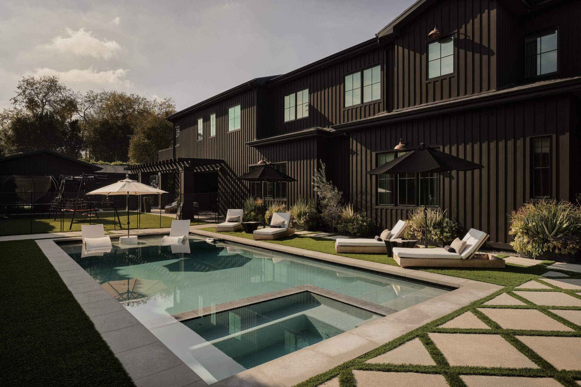 Stepping outside, the backyard opens into a clean, structured pool area that mirrors the home’s modern farmhouse exterior.