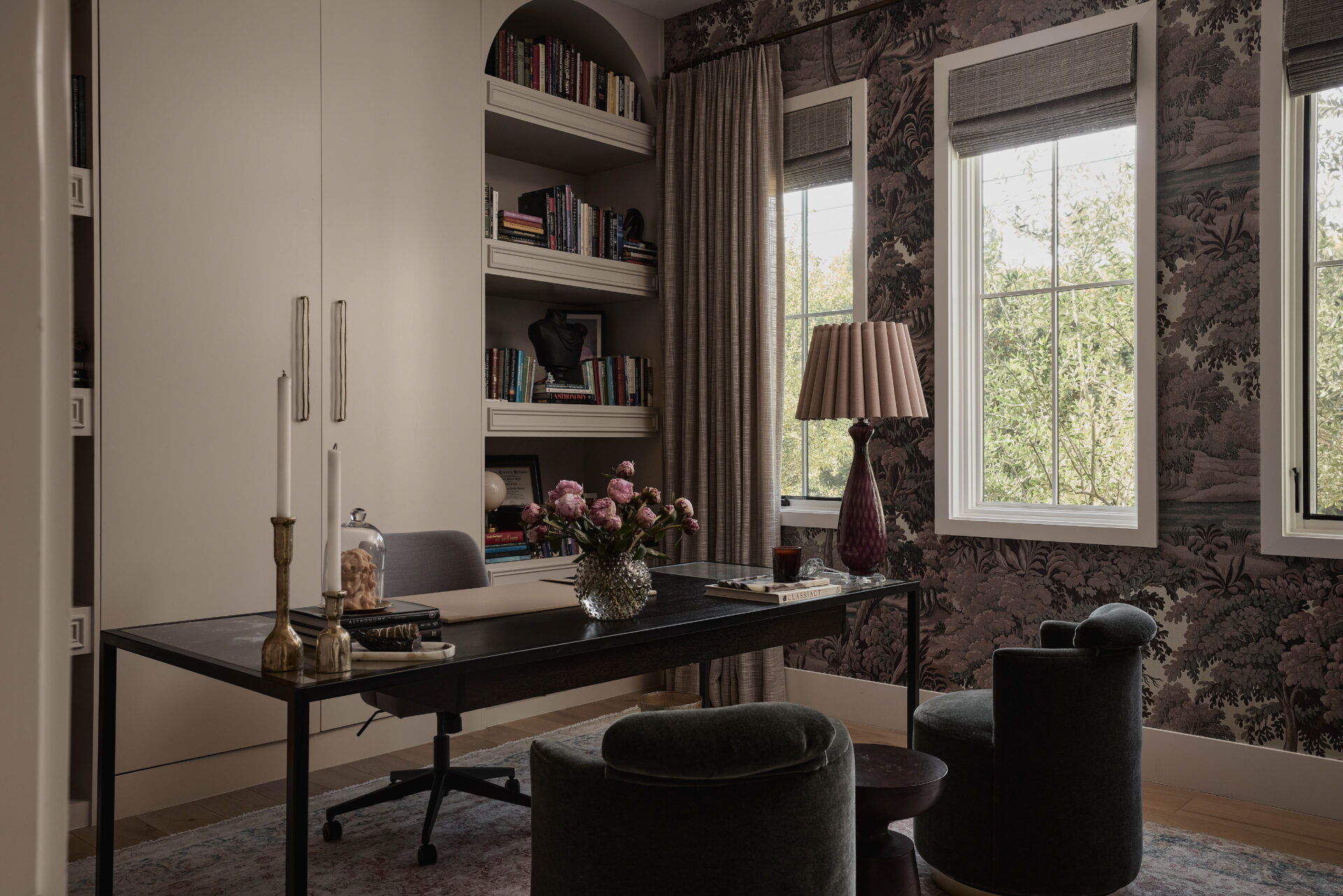 An office space where dark, moody finishes set the tone, paired with built-in shelving and a clean-lined minimalist desk. 