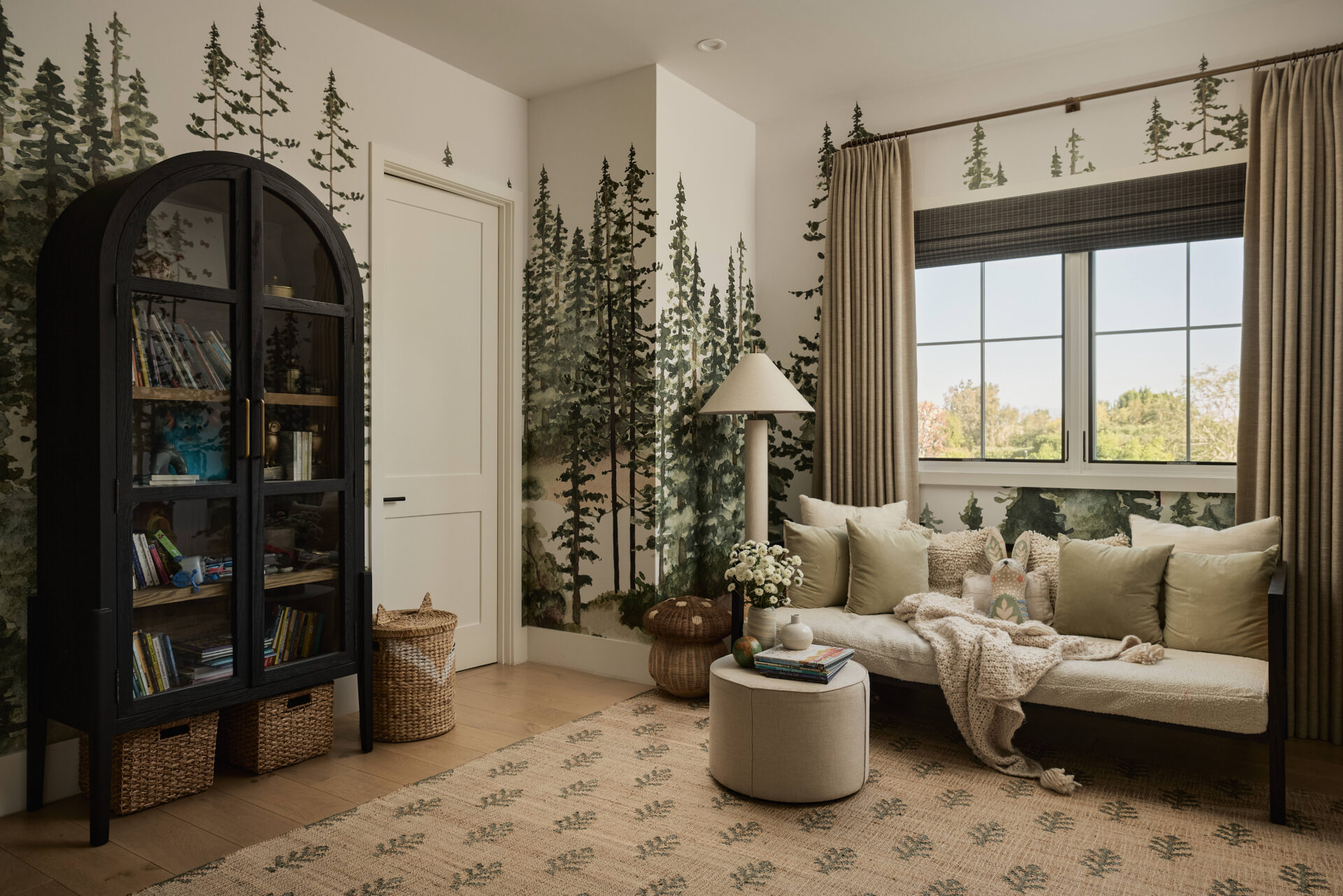 Kid's reading room with soft neutrals, forest wallpaper, and low, cozy seating.