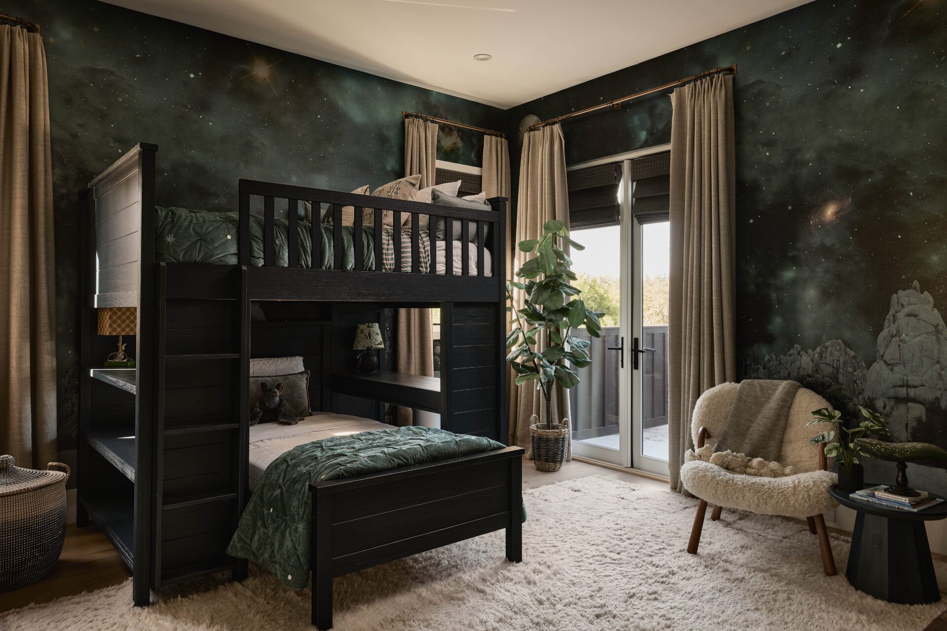 Kid's room wrapped in a celestial, galaxy-inspired wallpaper, with a black bunk bed.