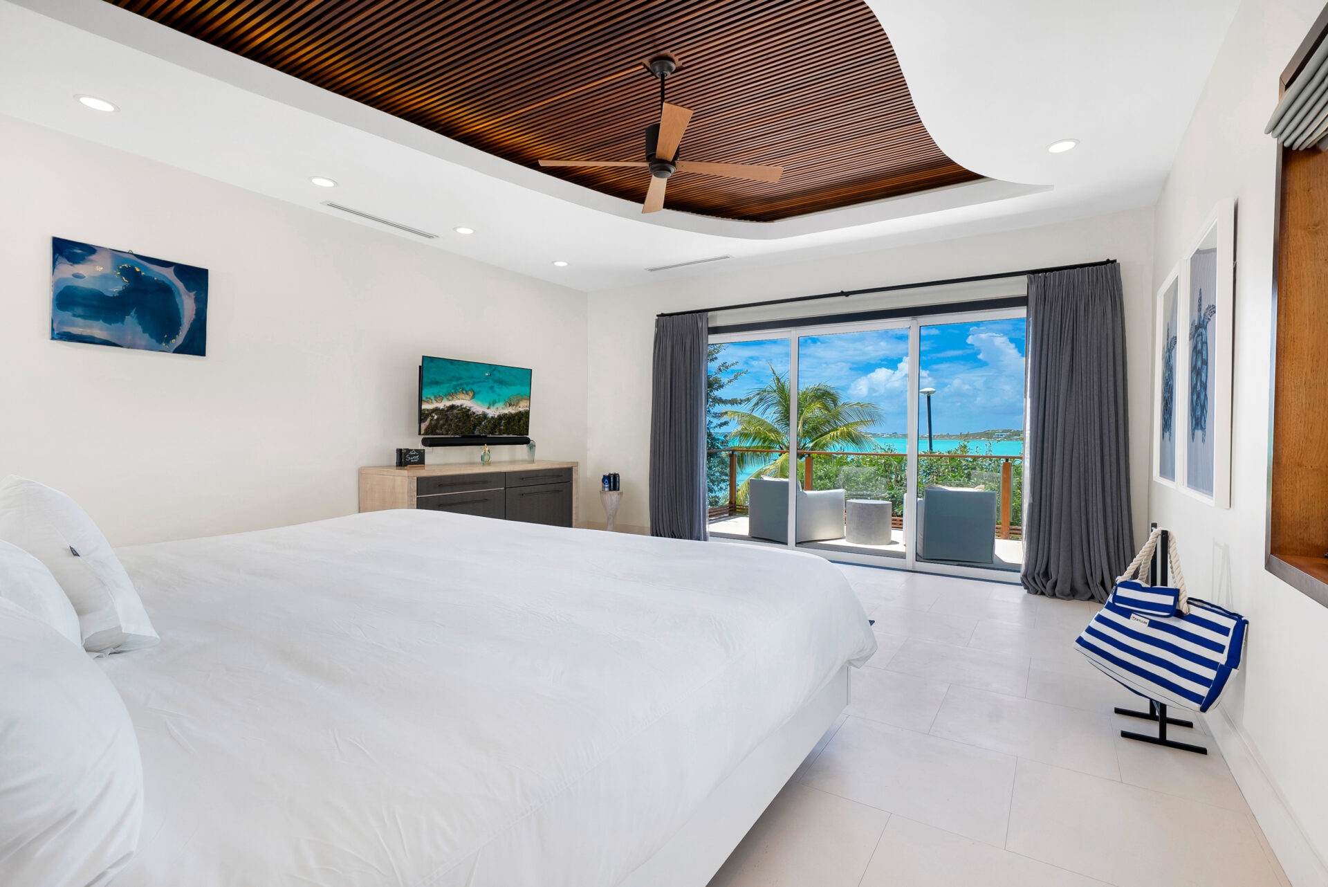 Bedroom with a nautical color scheme facing a private balcony facing the ocean.