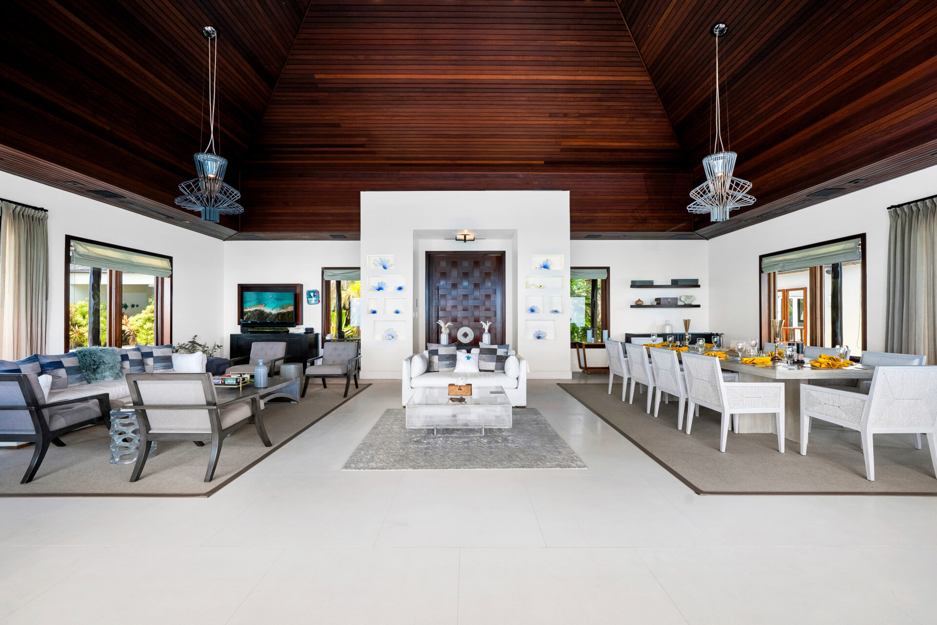Great room where vaulted wood ceilings rise above a symmetrical layout where the main living area and formal dining space sit across from each other.