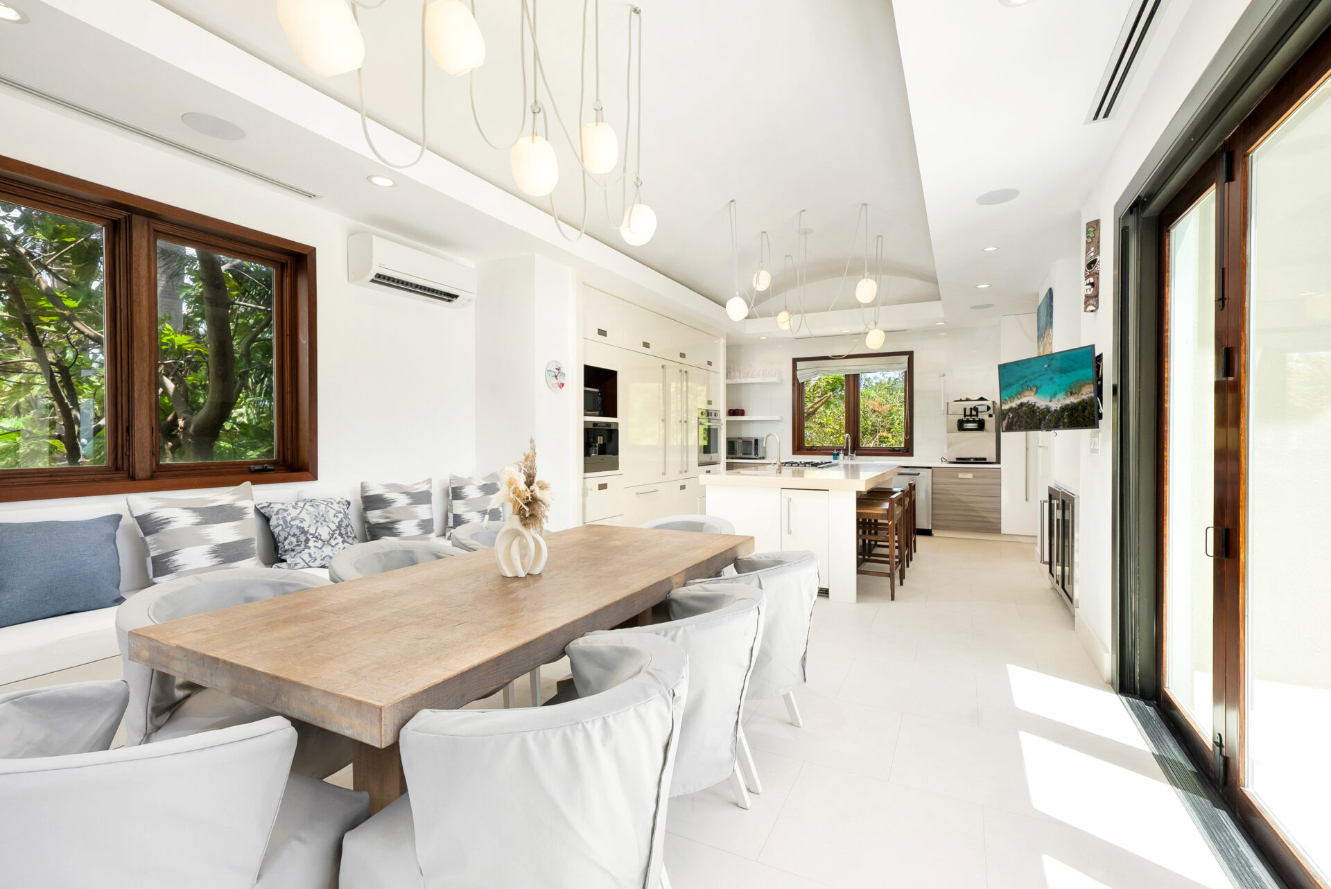 Clean white cabinetry, soft wood accents, a casual dining area, and a generous island fill the family kitchen.