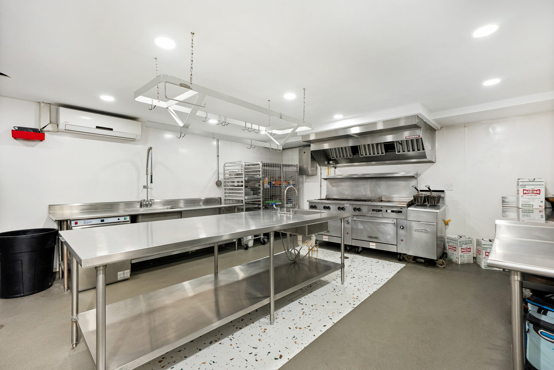 Professional grade kitchen with stainless-steel prep tables and commercial appliances.