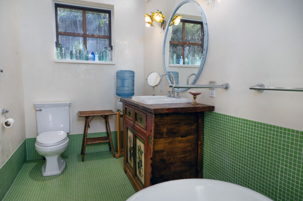 The bathroom is accessed directly off the bedroom and is finished with green tile that wraps the floors and lower walls.