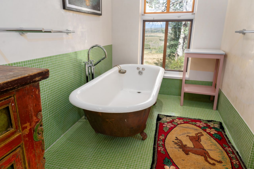 A freestanding clawfoot tub is placed beneath a window