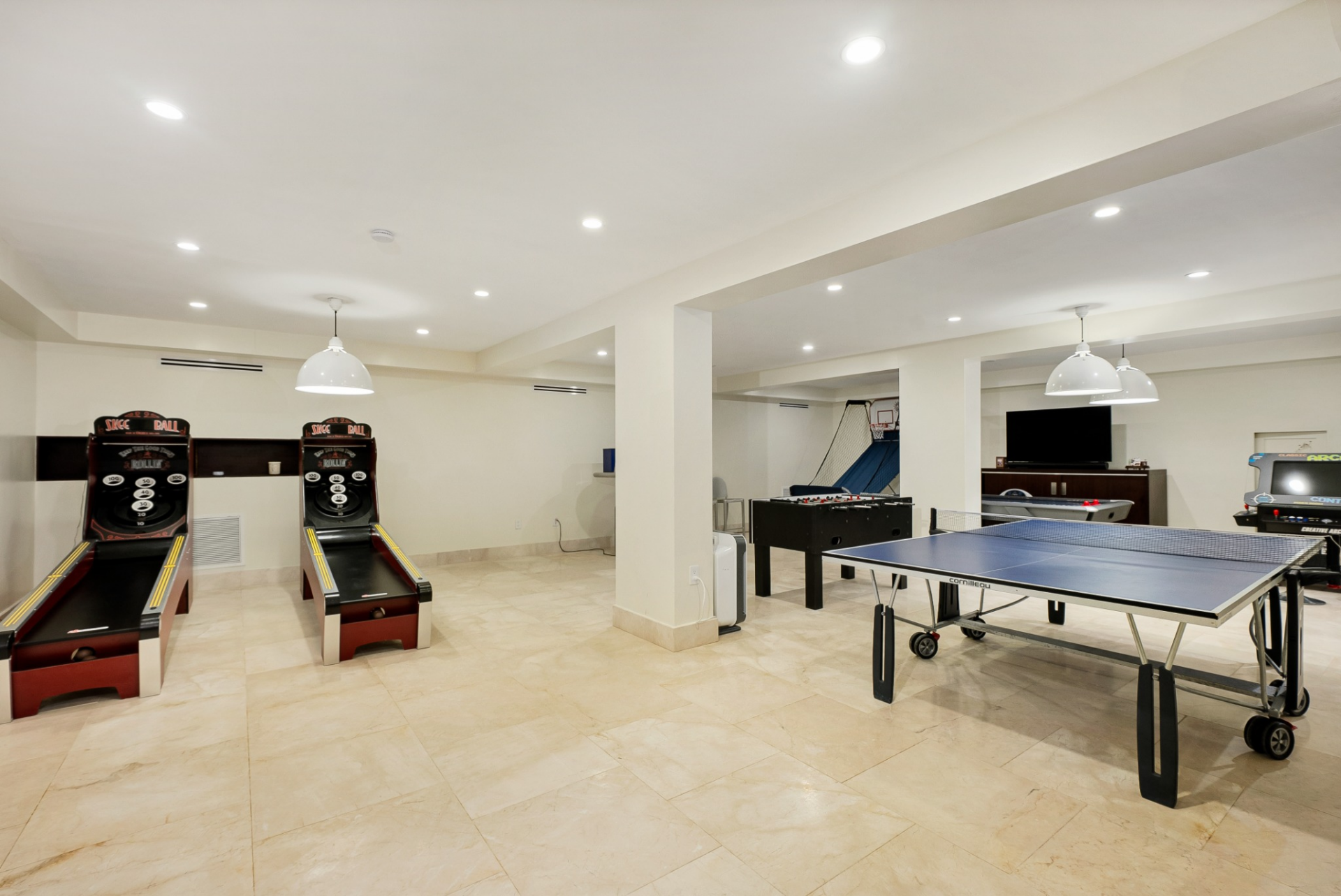 The game room features ping pong, skee-ball, basketball, and arcade-style games spread across a wide, open layout.