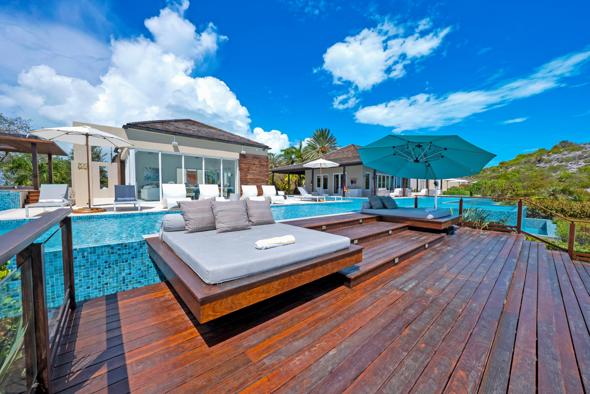 Daybeds and shaded seating zones placed along the perimeter of an infinity-edge pool.