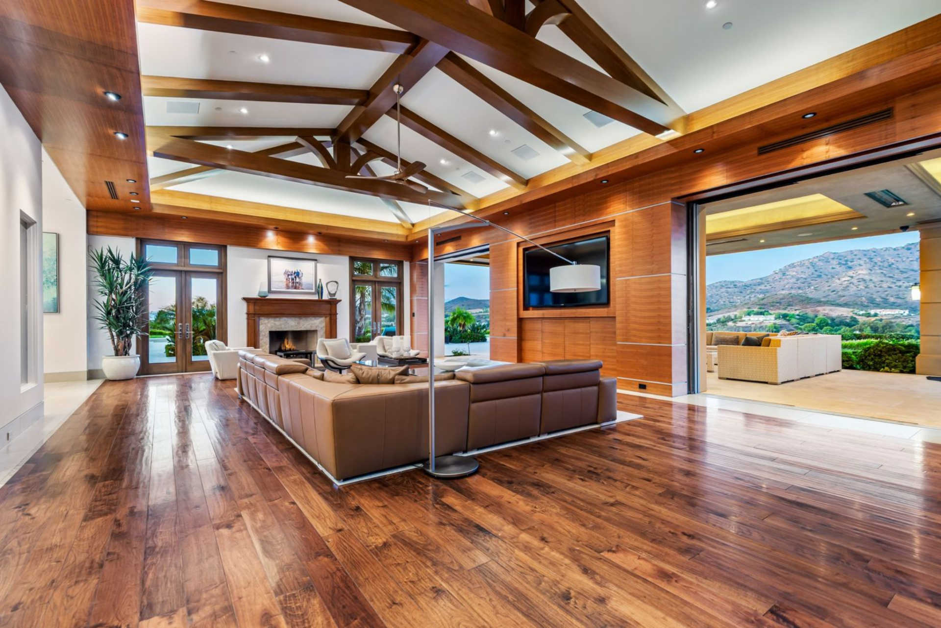 A deep sectional faces a built-in media wall framed by pocket doors that open to the outdoor living room.
