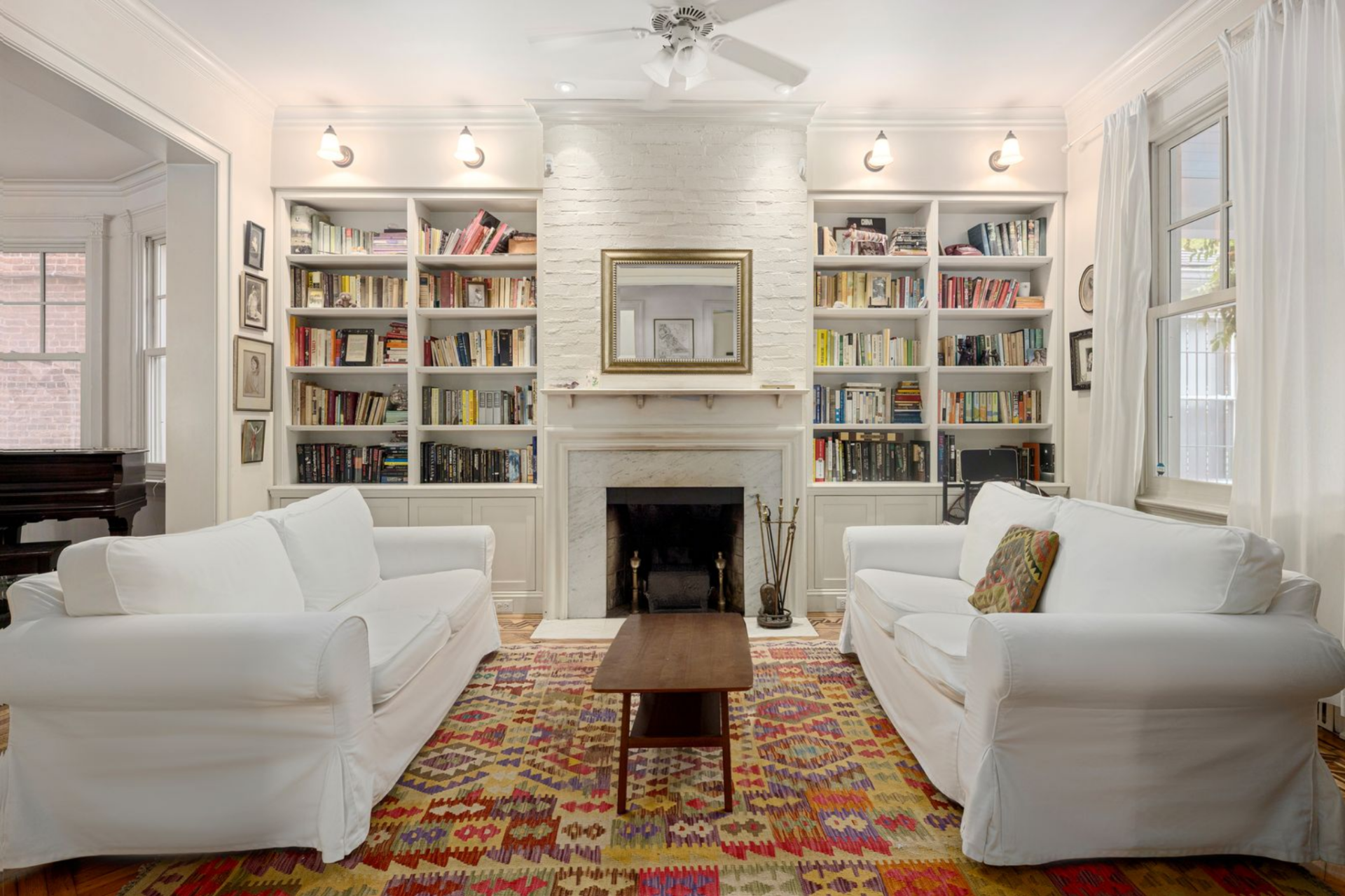 A marble, wood-burning fireplace sits between built-in bookcases that rise cleanly to the ceiling.