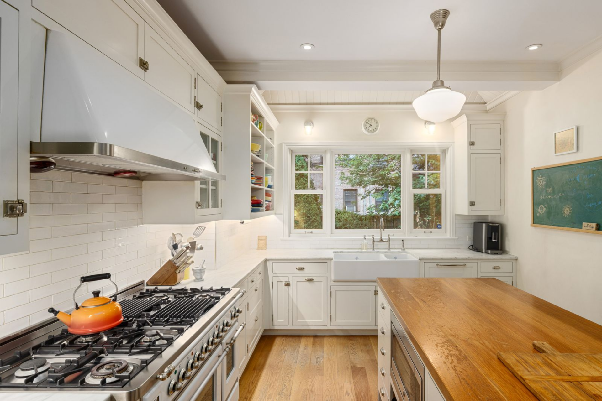 Kitchen with marble countertops that wrap the perimeter, paired with a large wood topped butcher-block island. 
