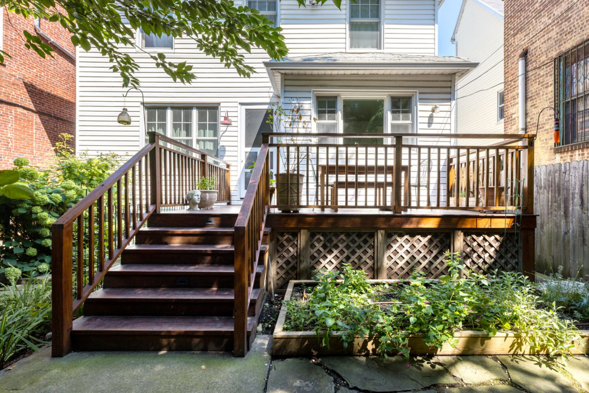 A dedicated vegetable and herb bed is arranged beneath the deck.