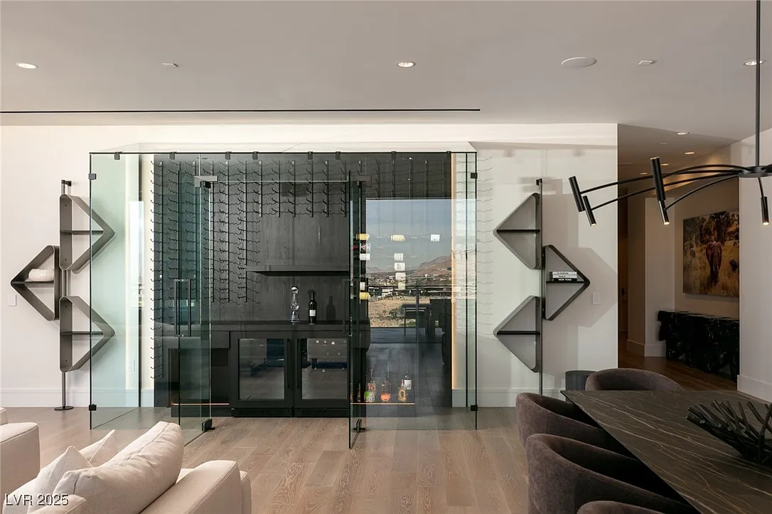 The side wall features a glass doored wine room with black metal racks, cabinetry, and wallpaper.