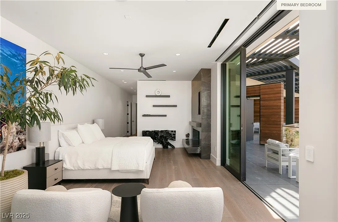The primary bedroom is anchored by a full-height stone fireplace wall, finished in dark slab stone with a linear gas insert opposite the bed. 