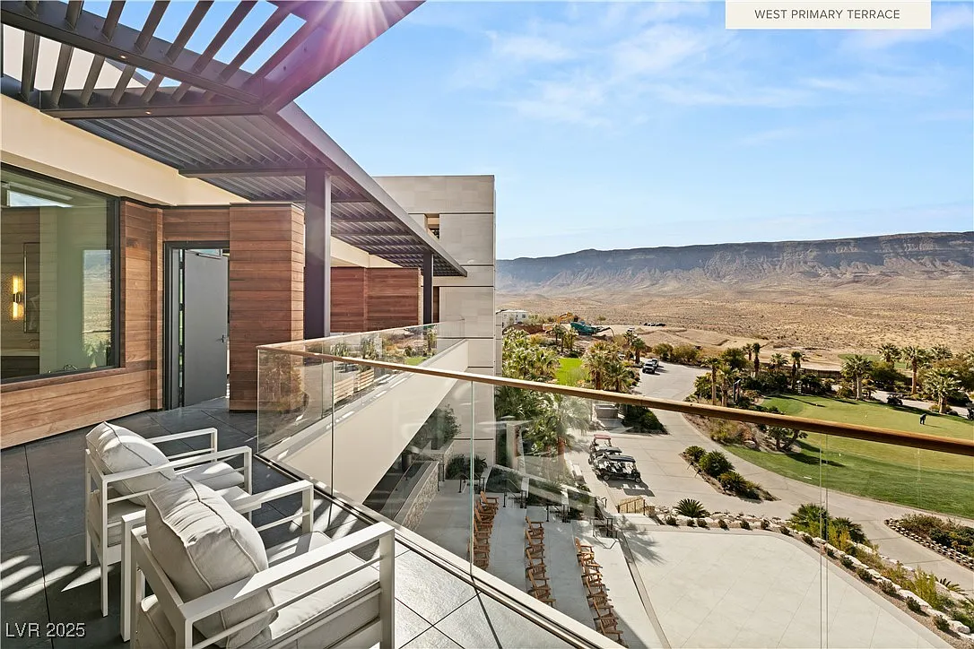 Wraparound terrace with glass railings looking towards a golf course and mountains.