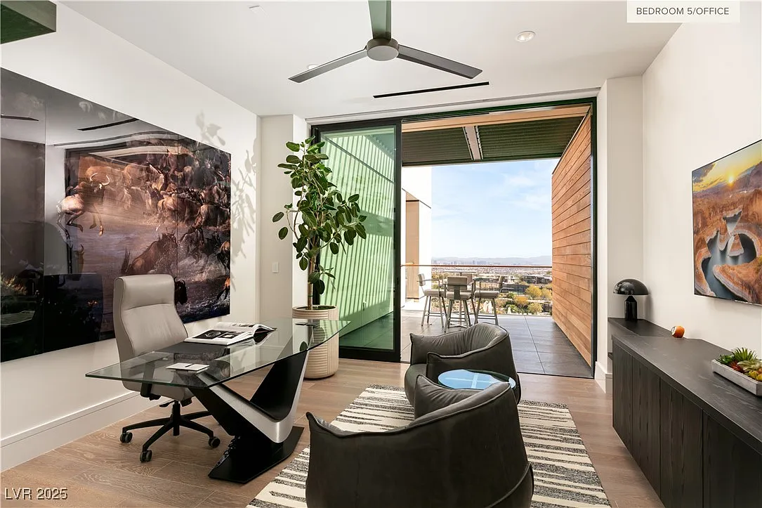 Home office with a sculptural glass desk positioned to face two cushioned lounge chairs with access to a private terrace.