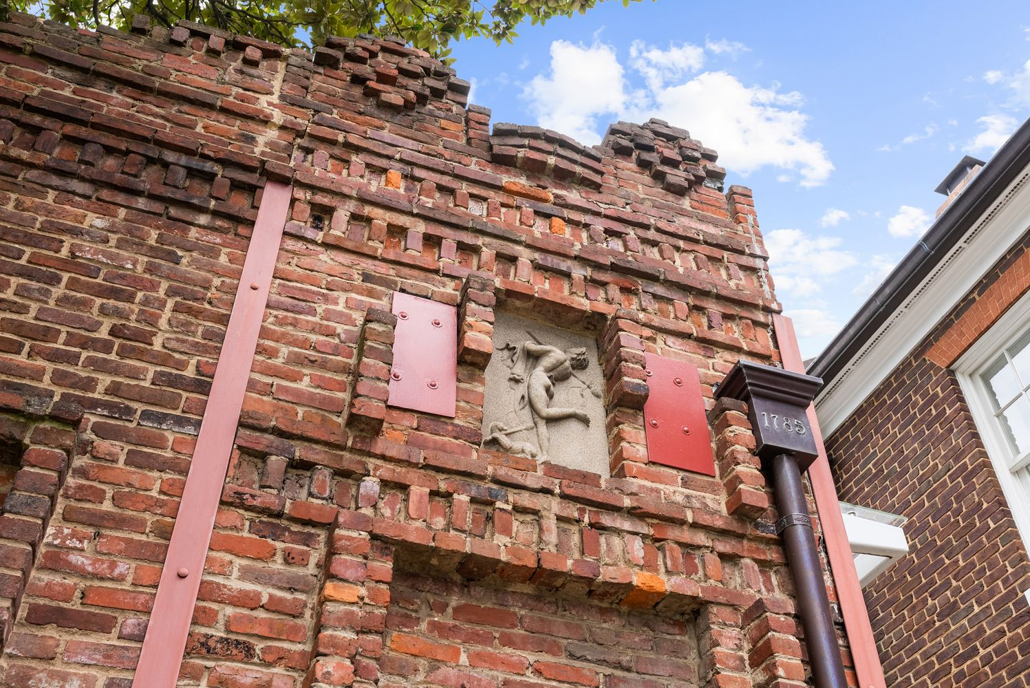 Tall red brick wall with an art sculpture.