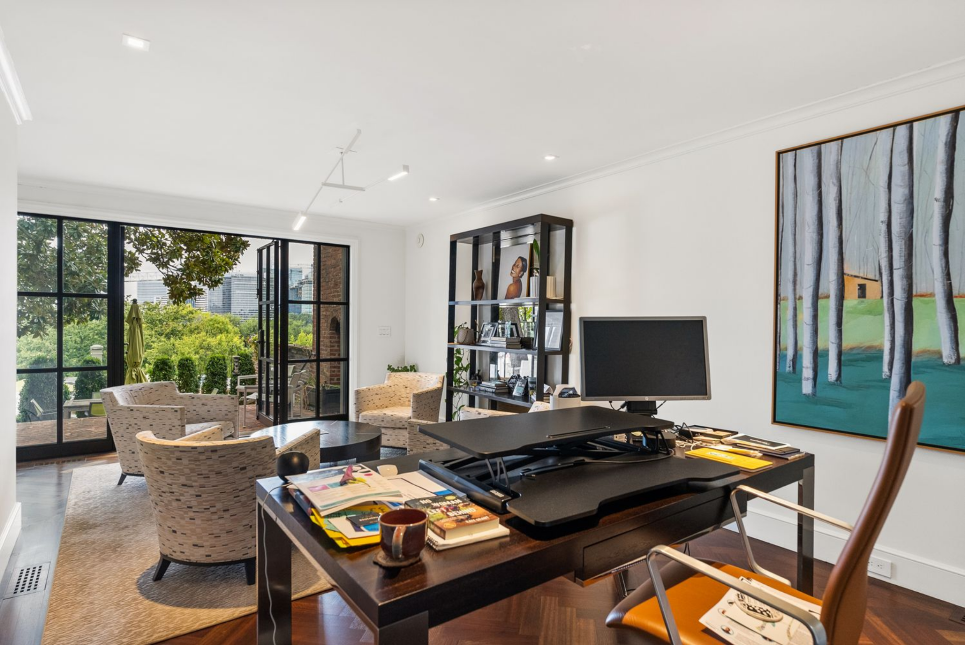 Private office with a modern desk, and curated seating looking out towards an open door to the gardens.