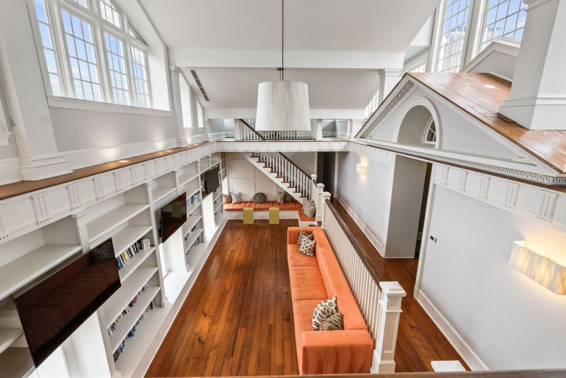 A perimeter gallery with turned balusters overlooks the library below, where wood floors contrast with crisp white paneling.