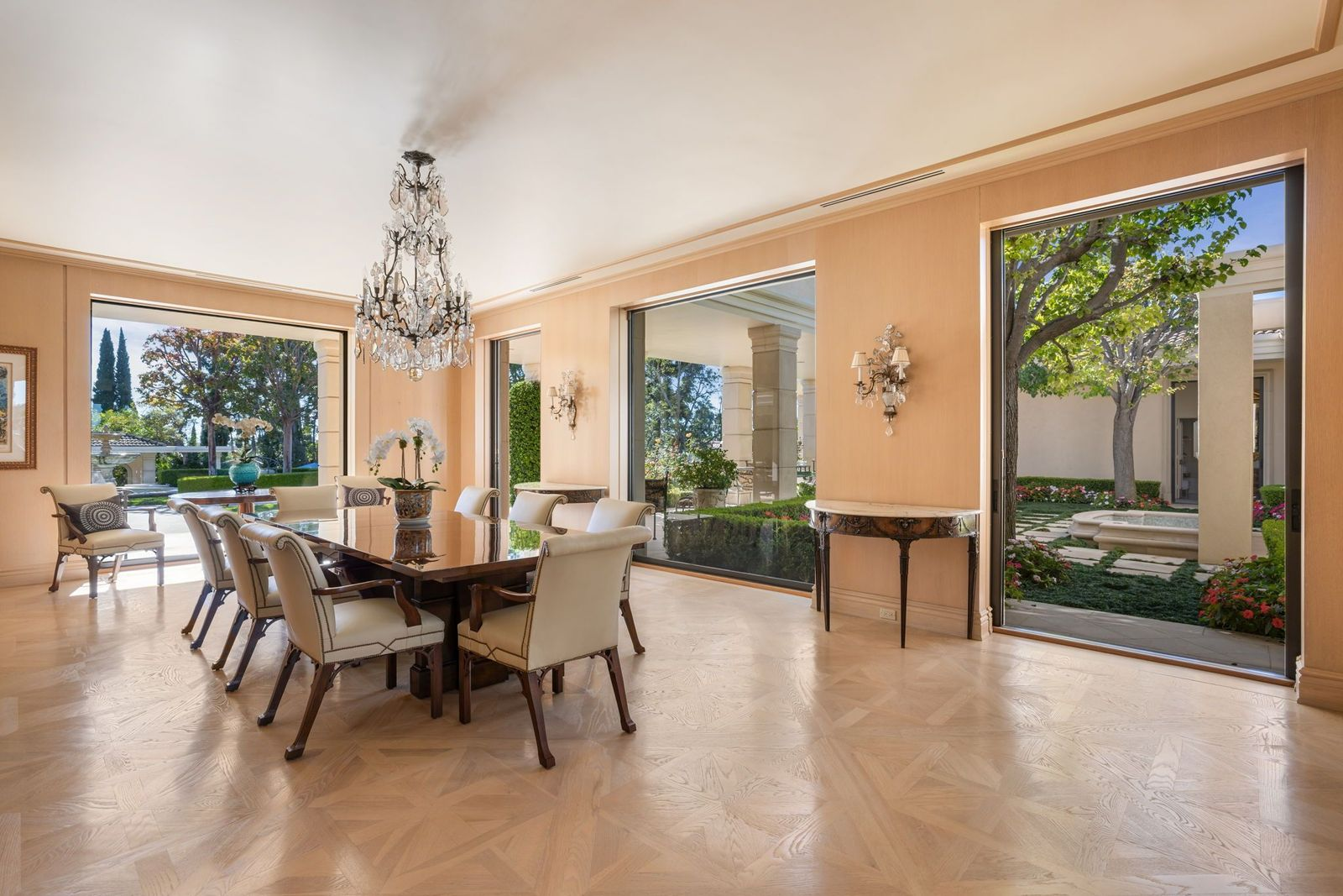Dining room with a crystal chandelier hanging centered over a polished dining table and glass pocket doors lining two sides of the room.