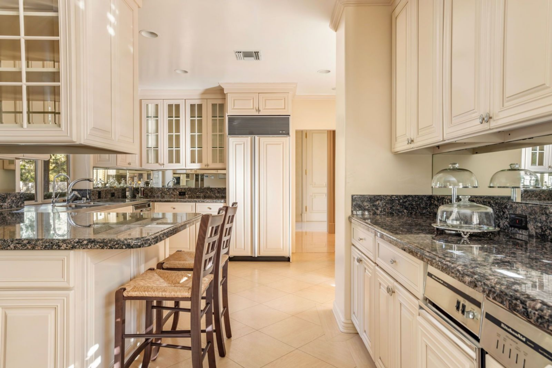 Kitchen with cream and glass cabinetry and a breakfast nook positioned beneath recessed lighting right in the center of the room.