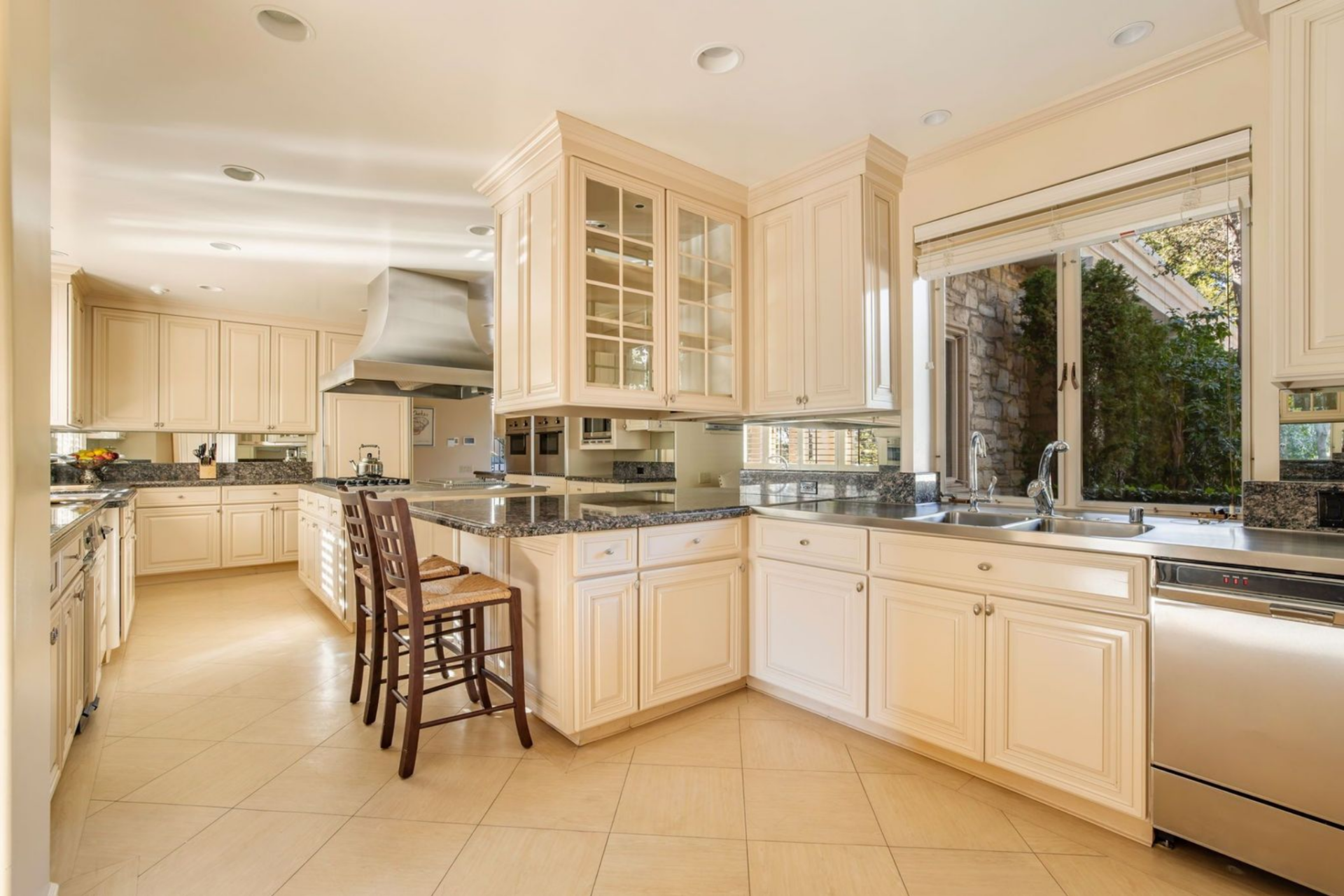 Stainless appliances are integrated cleanly into the cabinetry, including a professional-style range hood above the island. 