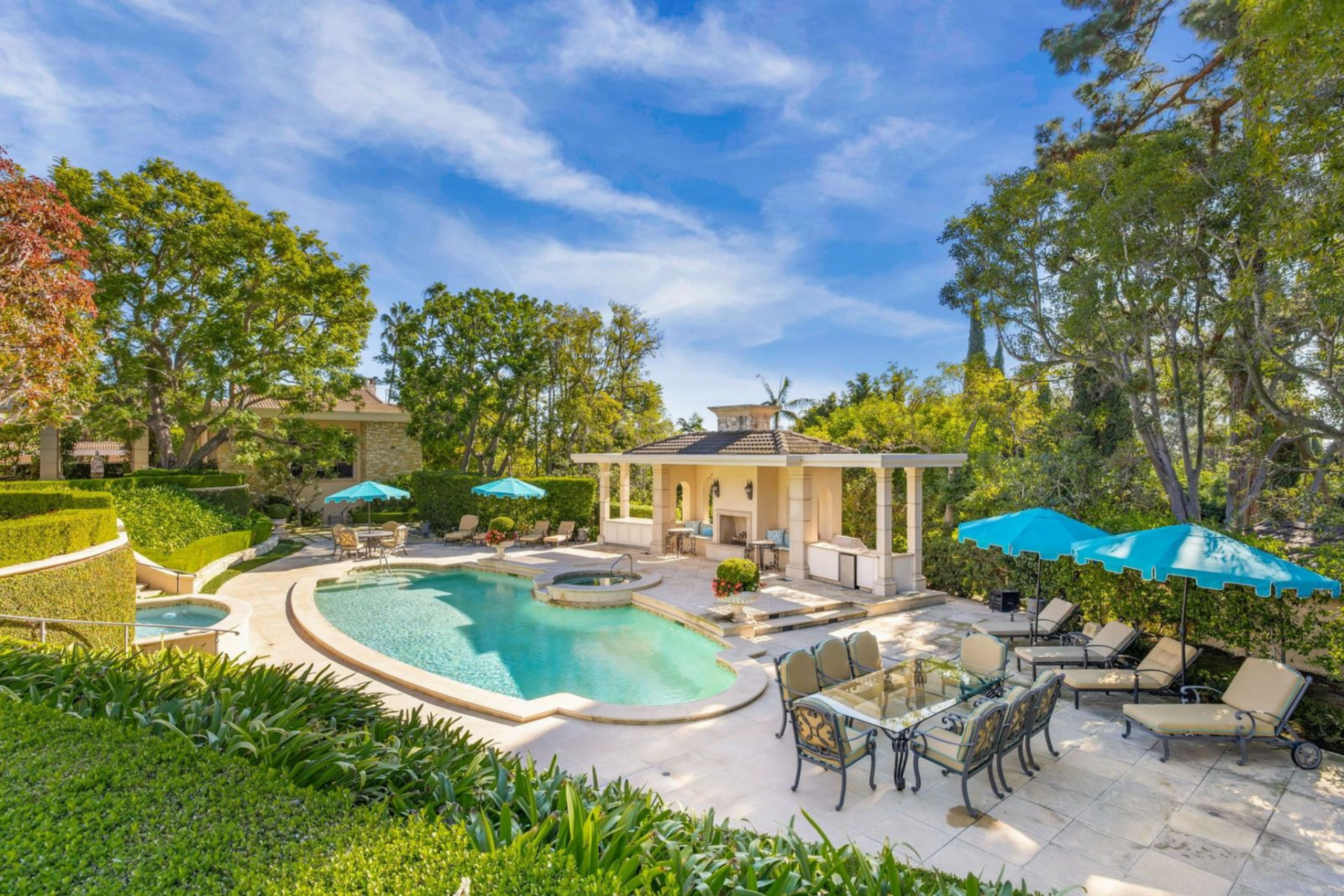 The oval swimming pool is paired with a sun deck and a cabana area, all set up for lounging and entertaining, with plenty of seating arranged around the water. 