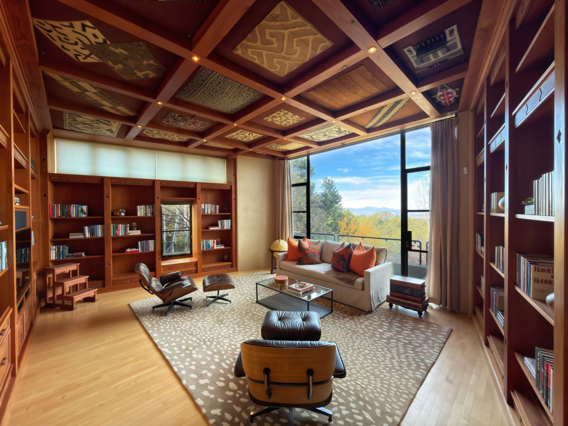The library is a very warm space, lined wall to wall with built-in shelves beneath a coffered ceiling with patterned panels.