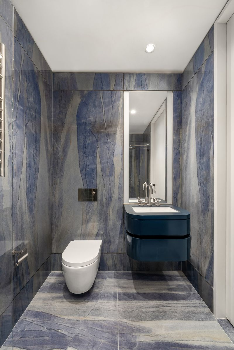 In the secondary bathroom, Azul Macaubas marble brings movement and color to the walls and floors with a floating vanity keep the focus on the stone’s natural veining.