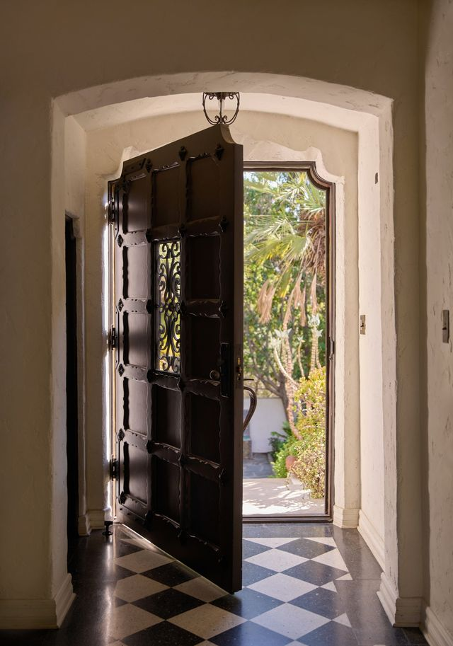 Arched entry and ironwork door open to the checkerboard tile floors that ground the space in its original era.