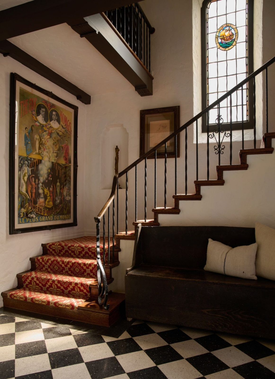Entry that honors the home’s history with a carved staircase and stained glass window.