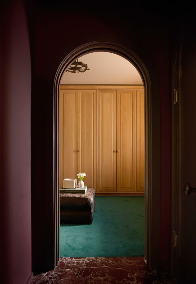A dedicated dressing area lined with floor-to-ceiling wood wardrobes and plush carpeting, adding a tailored, intimate finish to the suite.