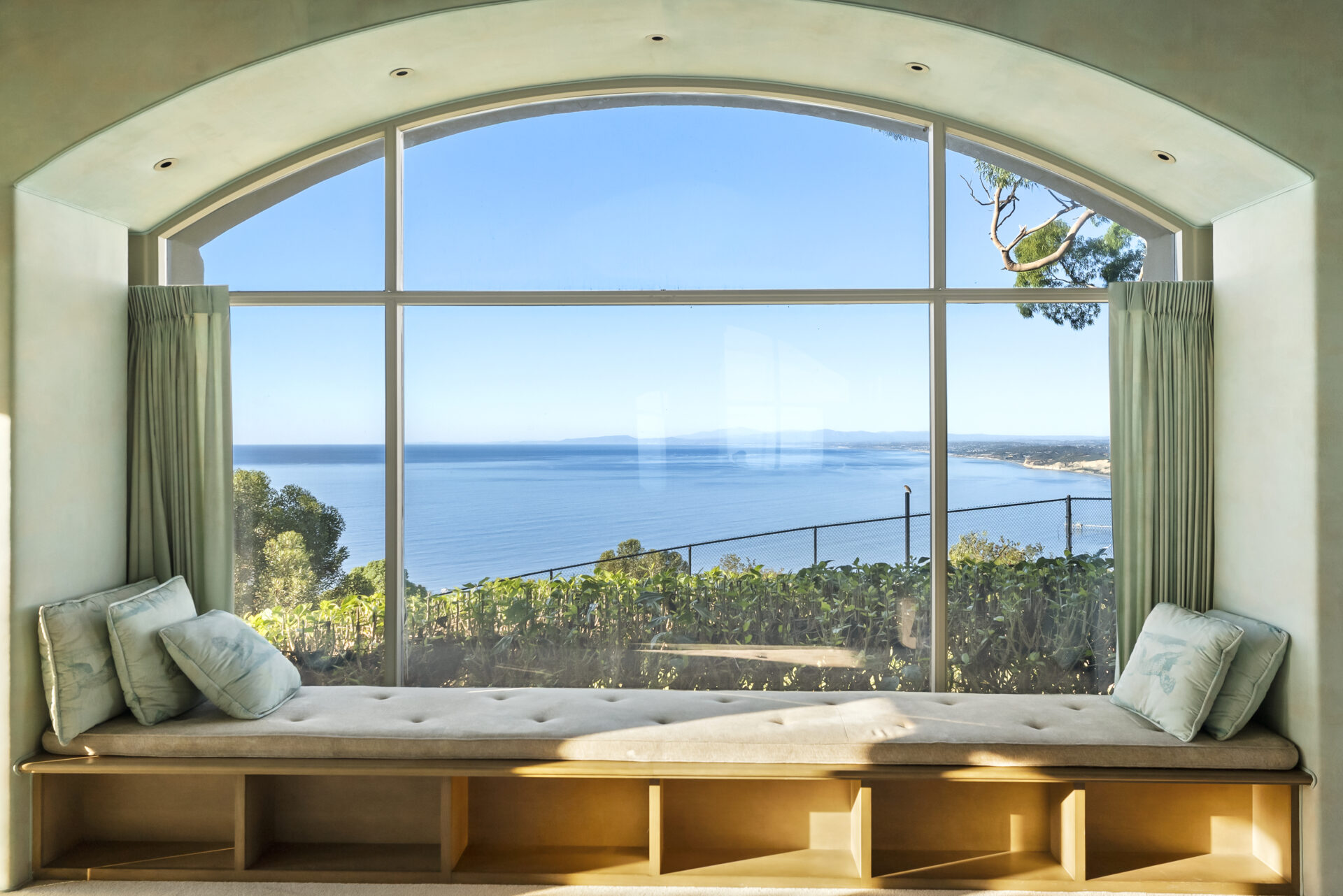 Built-in window seating runs the length of an arched window, and sliding doors open directly to the outdoors.