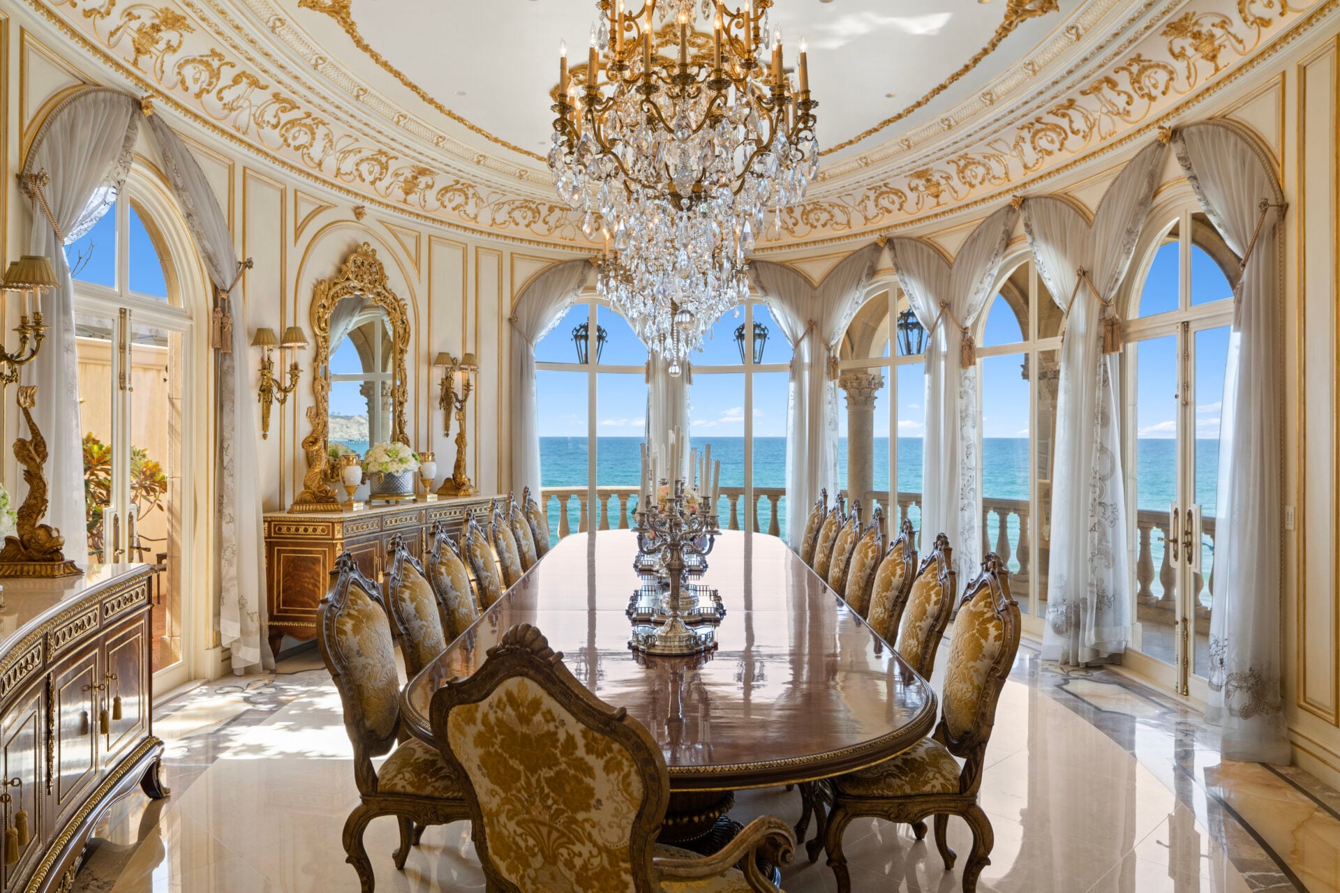 Down the hall, the formal dining room is one of the most beautiful rooms in the estate, with its extensive use of solid gold leaf, applied across the wall moldings and gilded detailing.