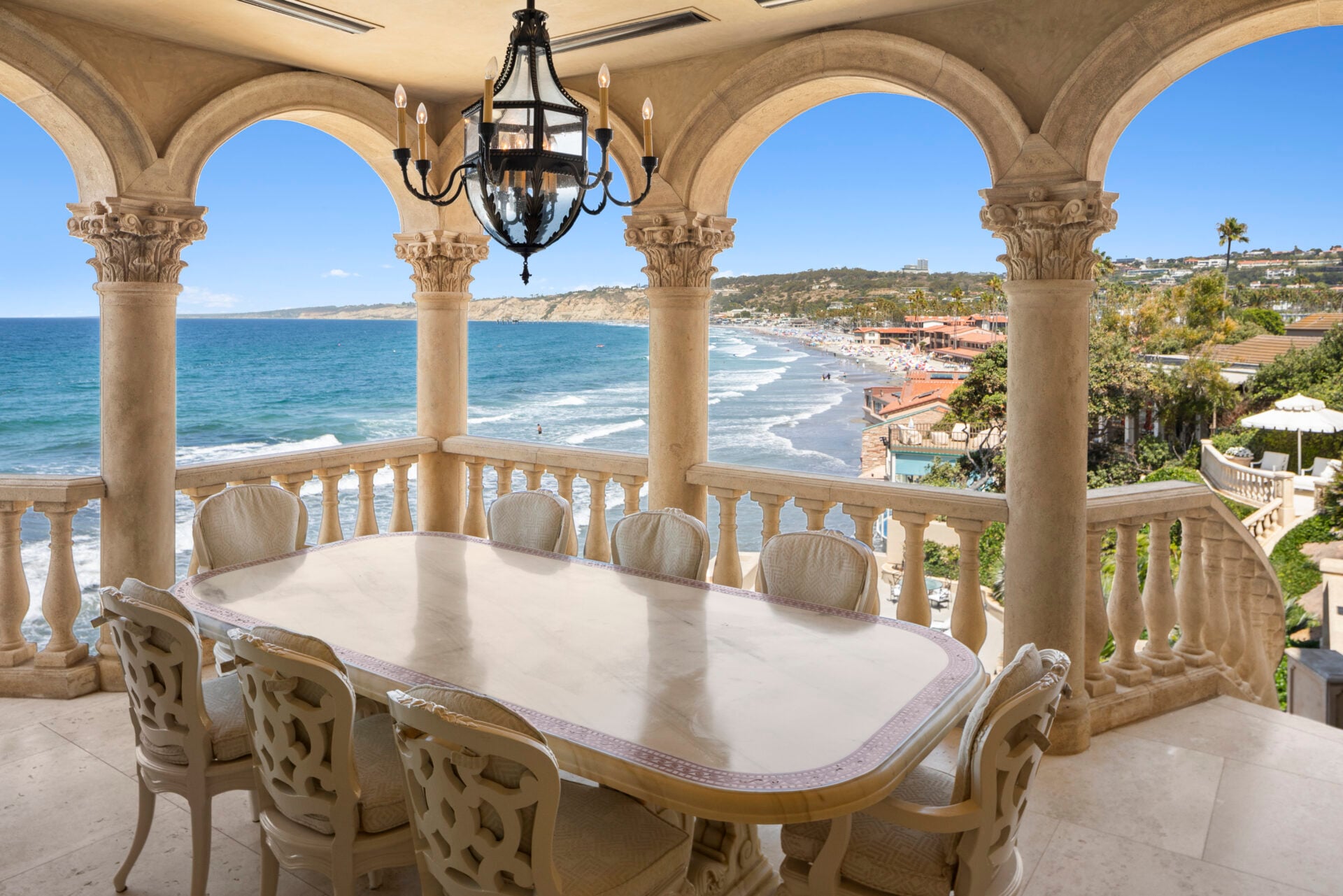 Outdoor dining terrace with ocean views through arched columns.