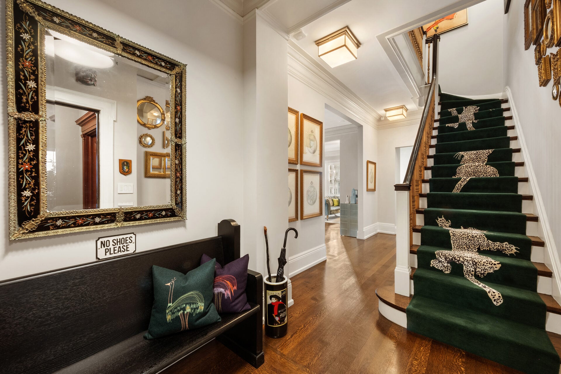 The elegant entry foyer opens with a sweeping staircase wrapped in deep green carpet that curves upward, guiding you naturally through the home. 