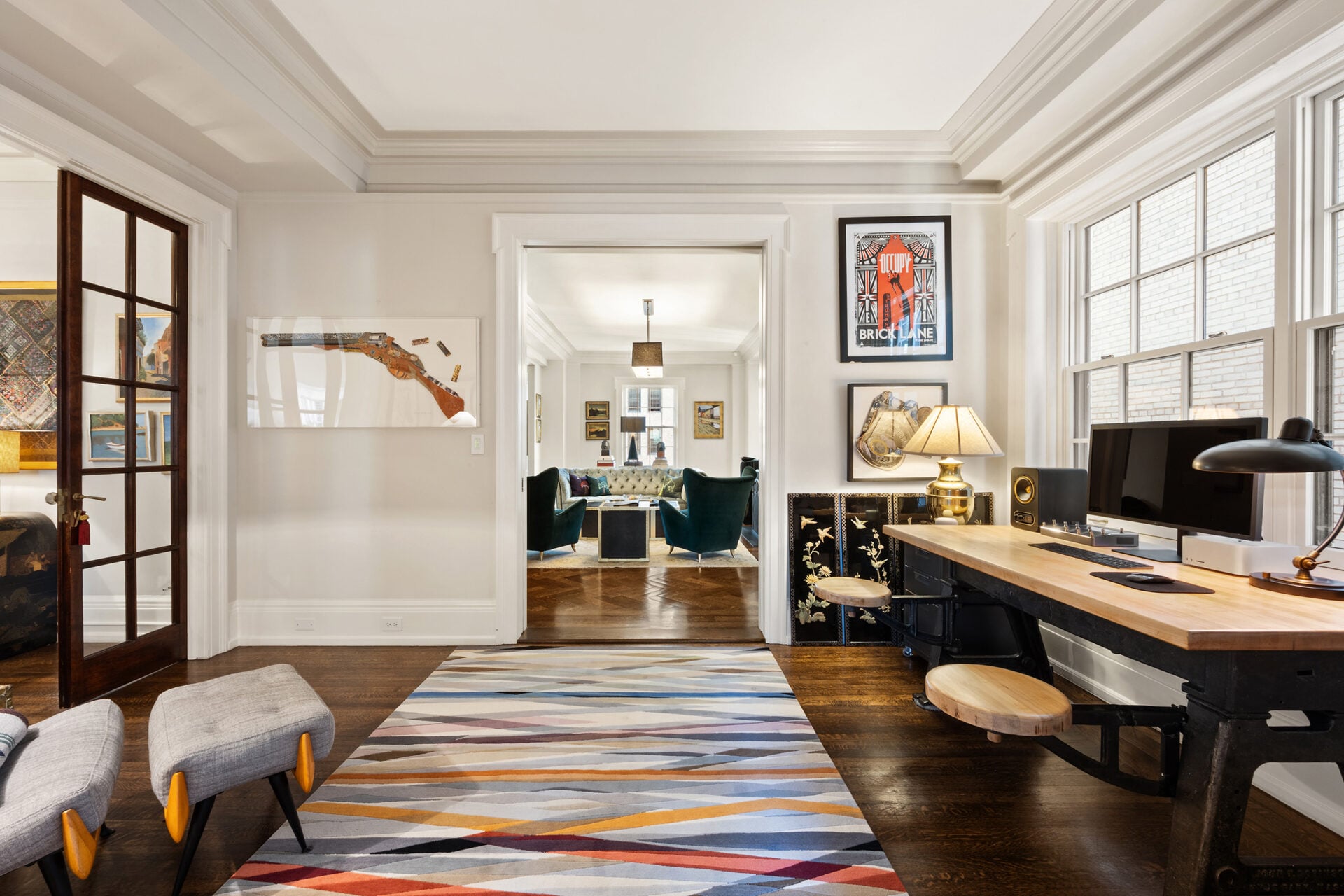 The home office is set against large windows that bring in steady natural light, while custom millwork and a substantial desk ground the room