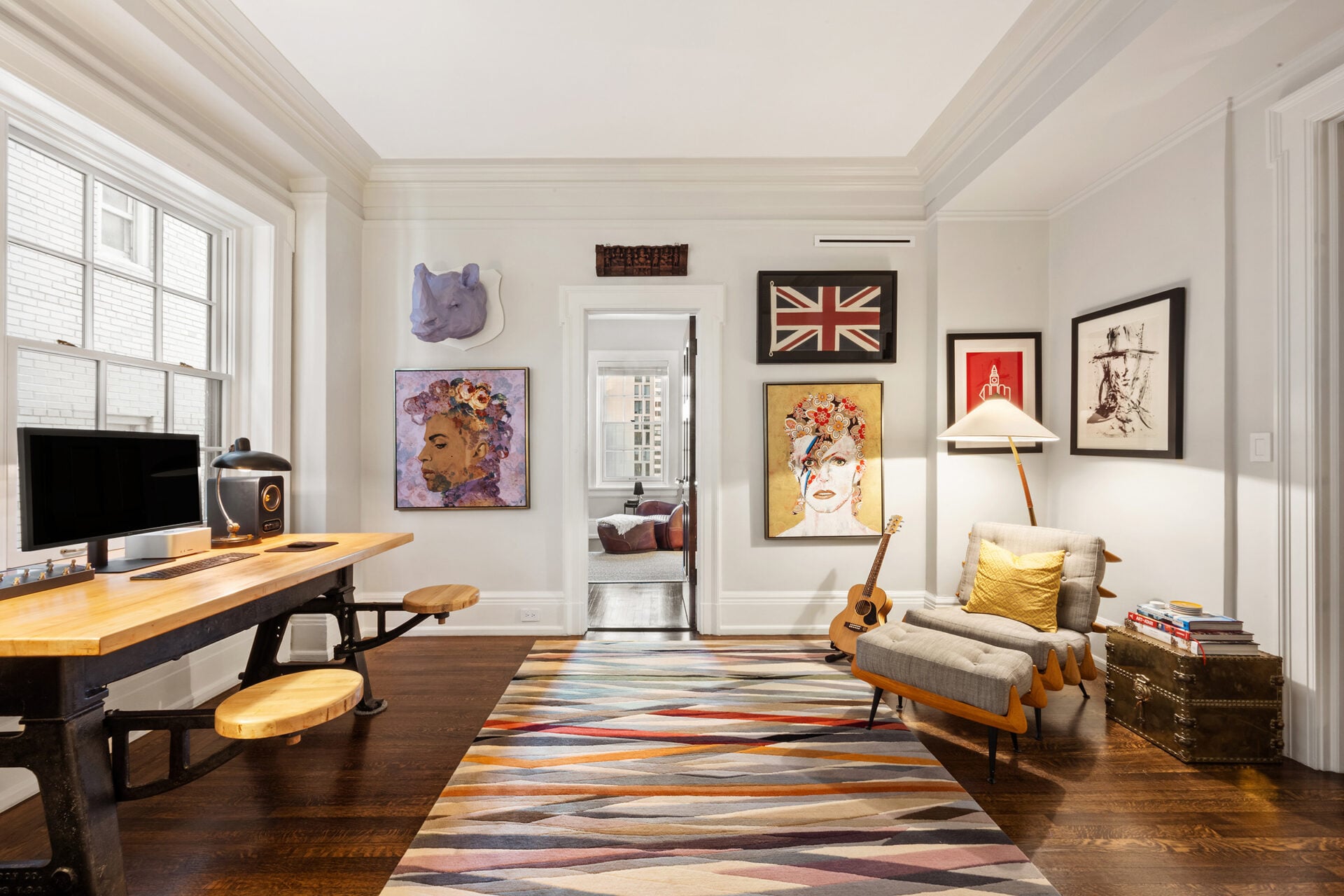 The layered artwork, vintage accents, and warm wood floors keep the space from feeling formal, instead giving it the character of a private study.