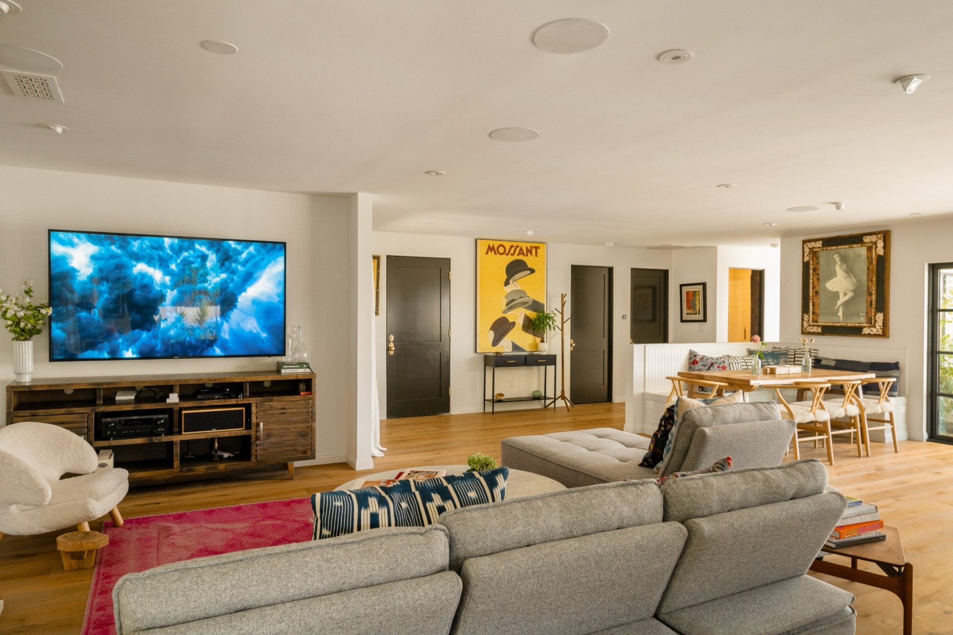 The first space in the open floor plan is the living room, featuring low, inviting seating arranged to face both the artwork-lined walls and the TV. 