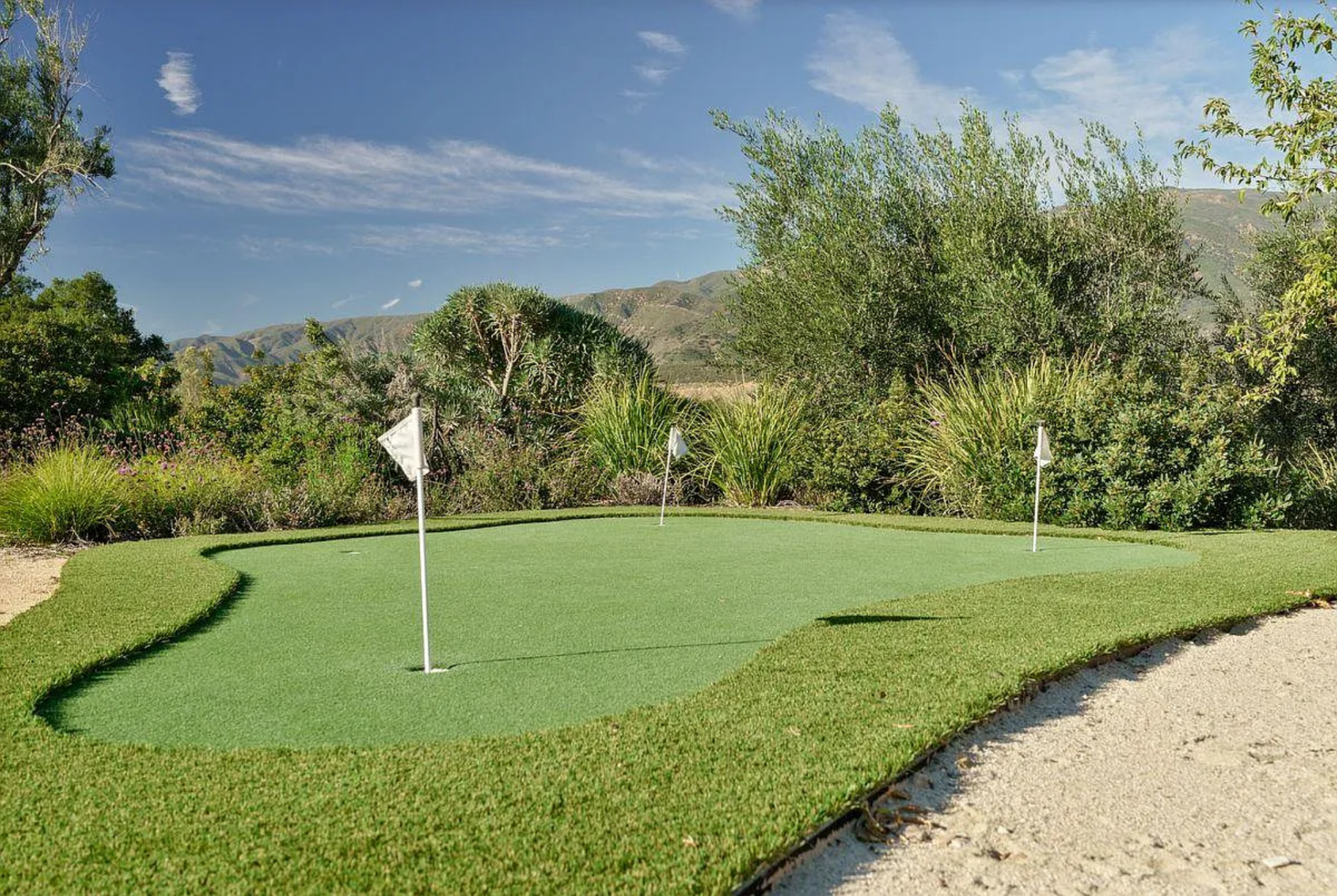 A custom putting green sits along a gravel path, offering a low-key practice spot woven into the natural setting.