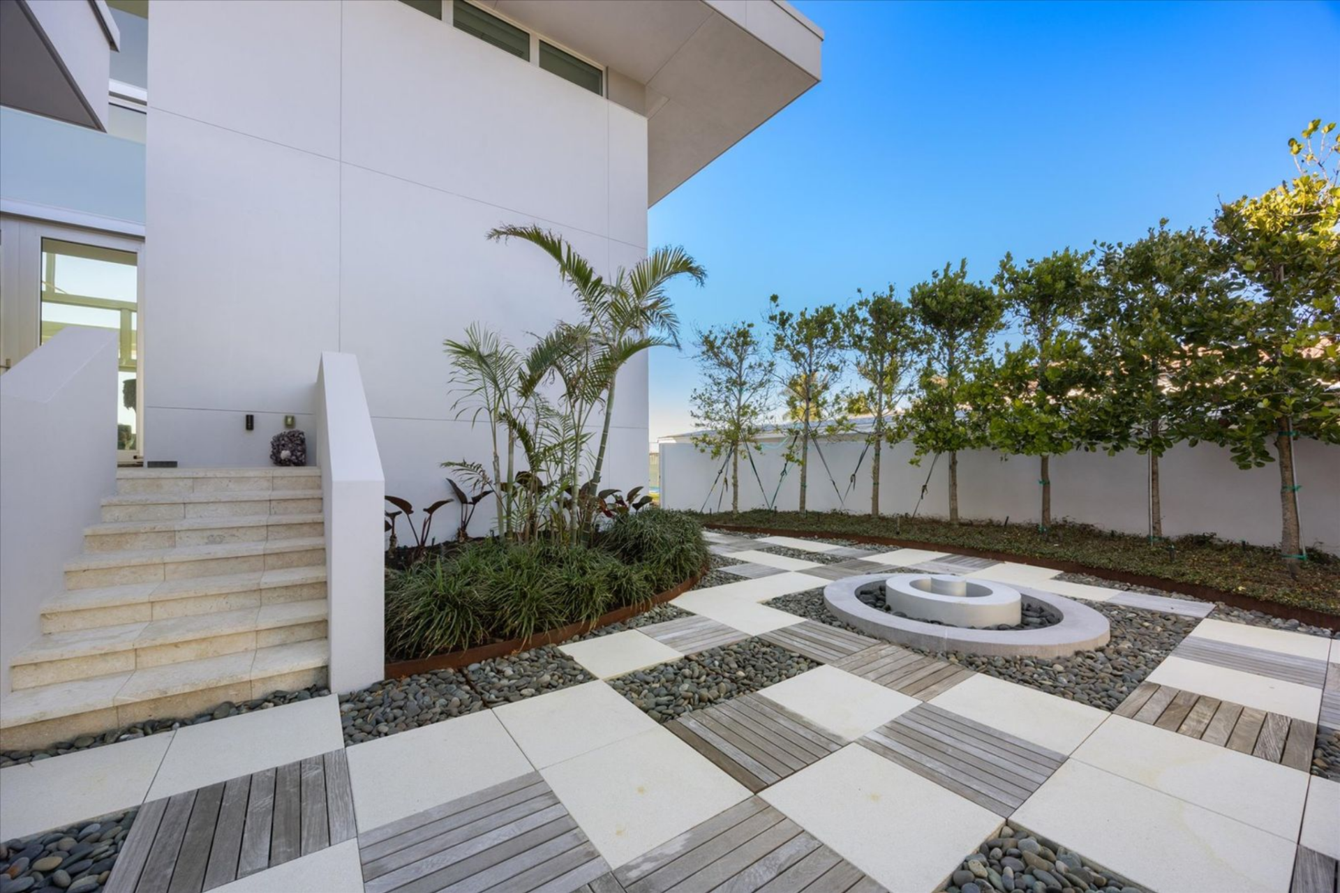 Framed by clean white walls and carefully placed greenery, this quiet outdoor space acts as a buffer from the street.