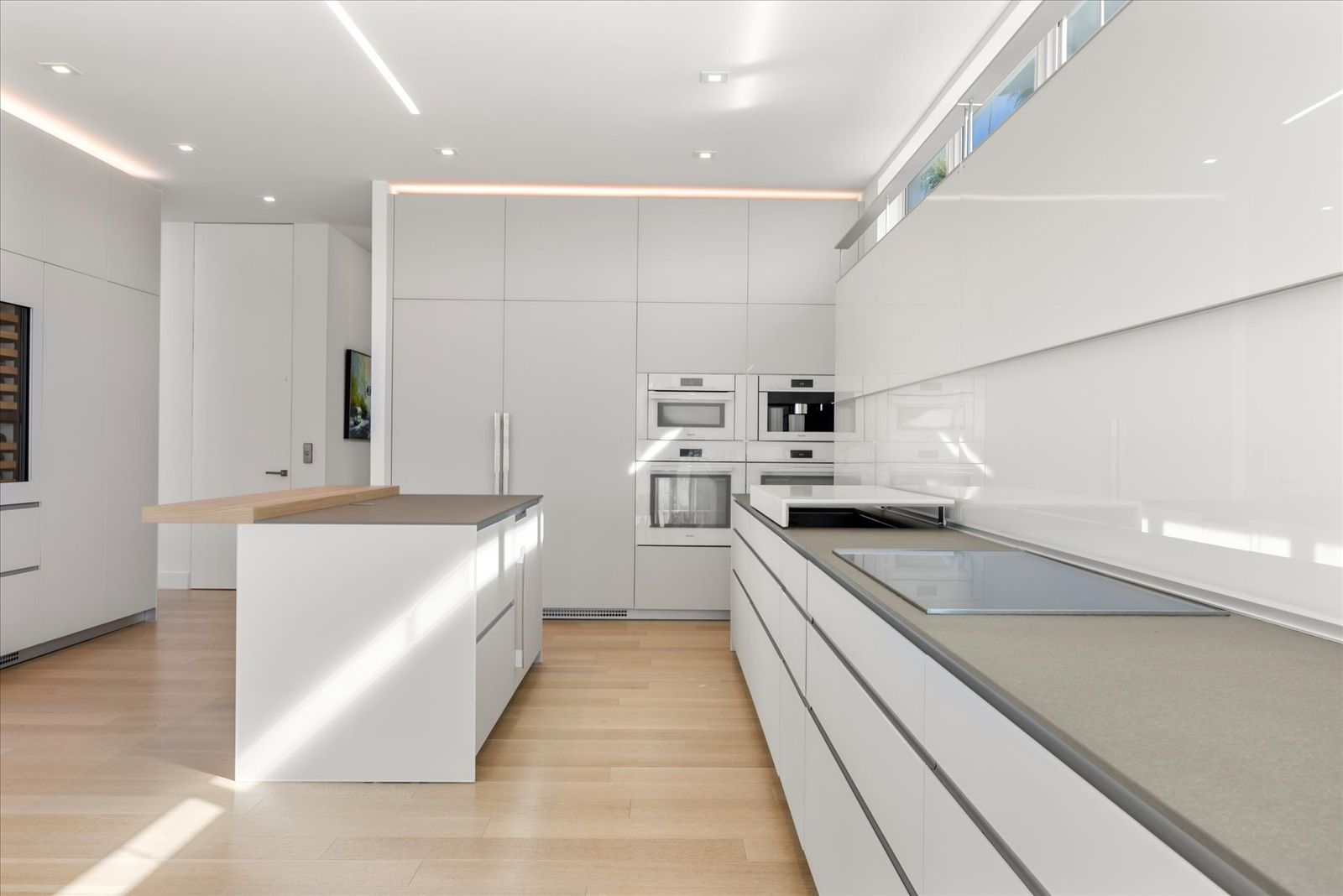 Granite countertops and a sliding cooktop surface emphasize clean lines and flexibility, while a full suite of Miele and Sub-Zero appliances is integrated into the layout. 