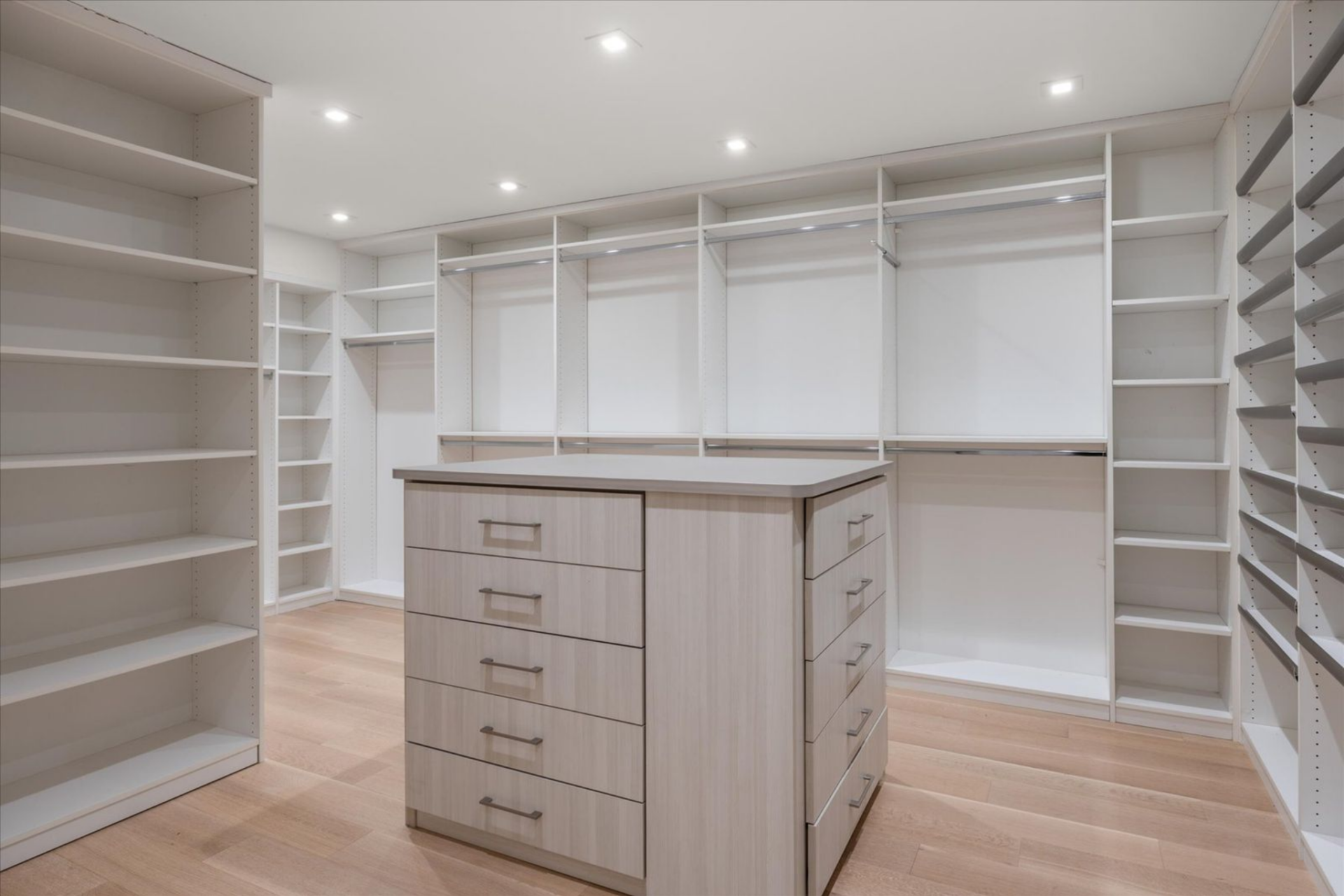 The suite includes custom walk-in closets, each thoughtfully built out with shelving, hanging space, and a central storage island. 