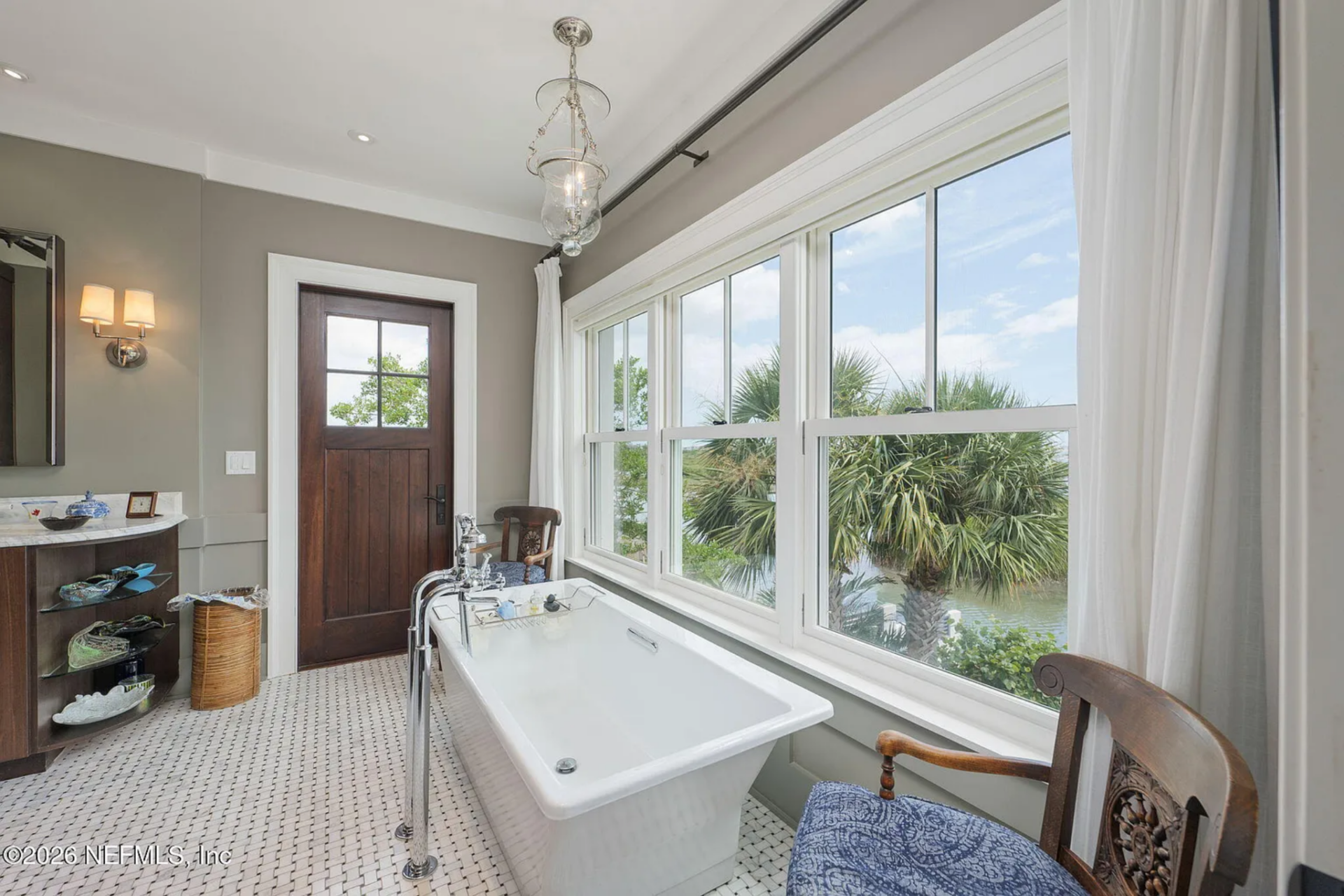The en-suite bathroom continues the suite, beginning with a freestanding soaking tub placed directly beneath a row of large windows.