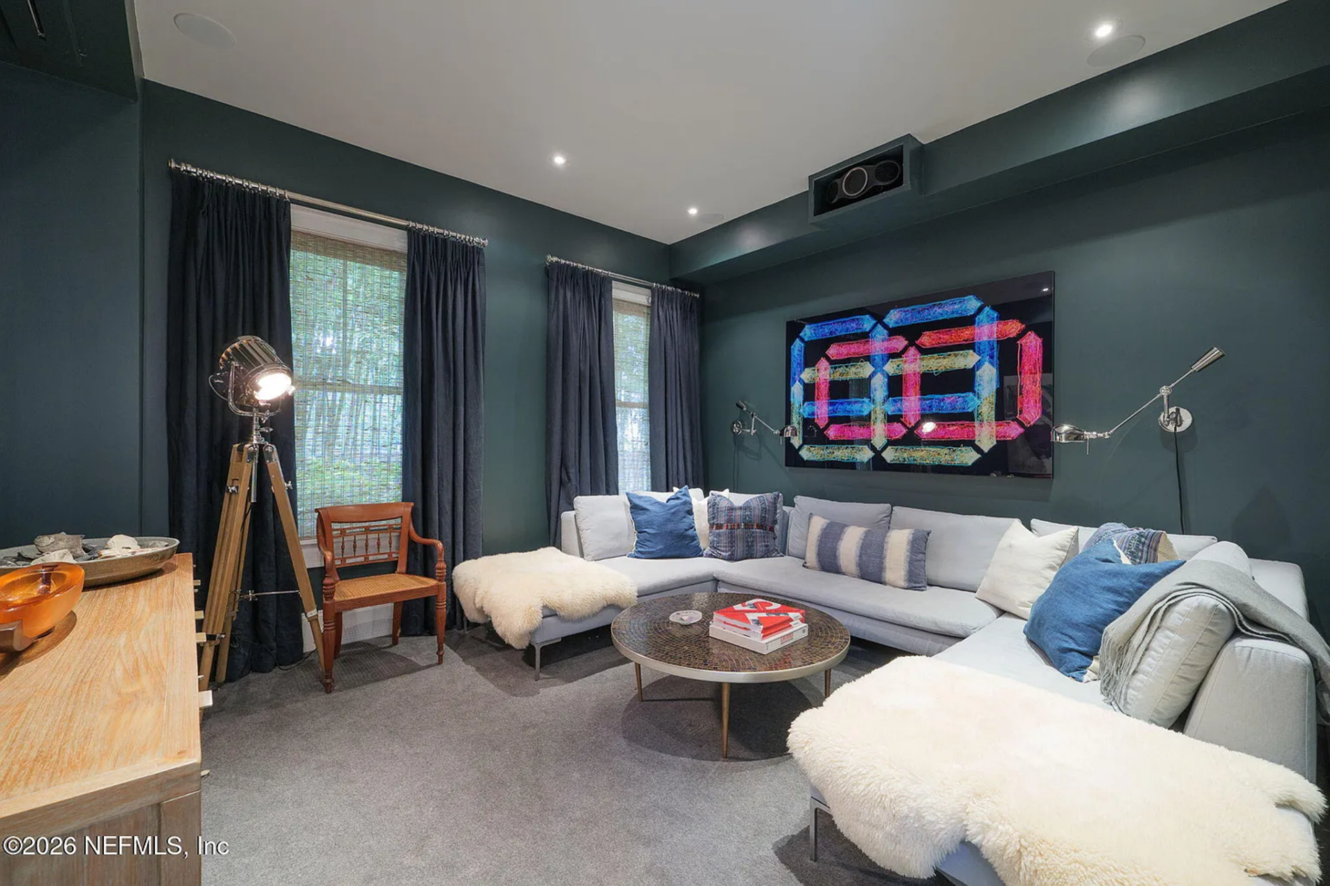 A large sectional wraps around the room, layered with textured throws and pillows, and centered around a low round table.