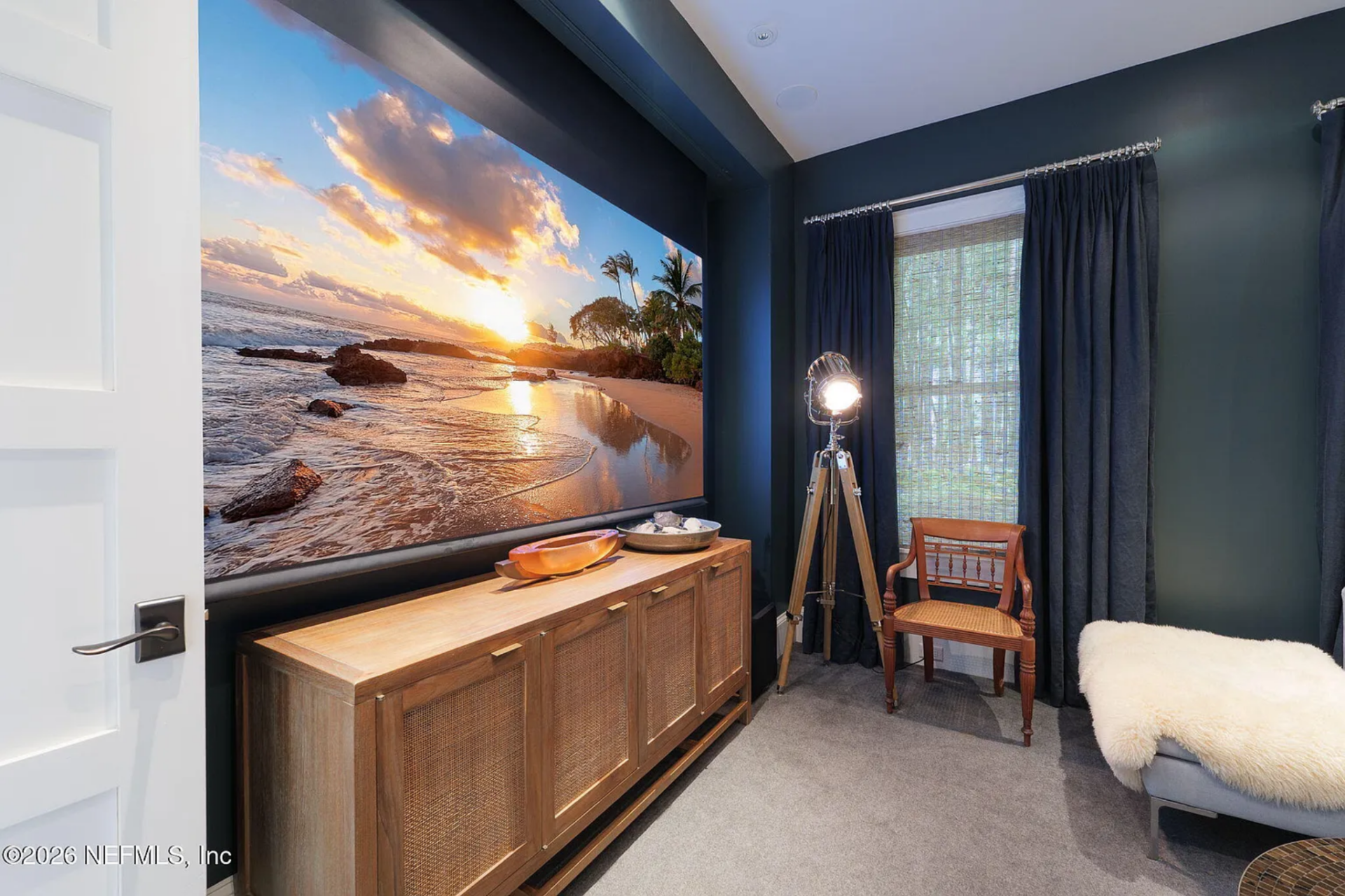 Along one wall, a wide console sits beneath a large screen, balancing the scale of the room and providing concealed storage.