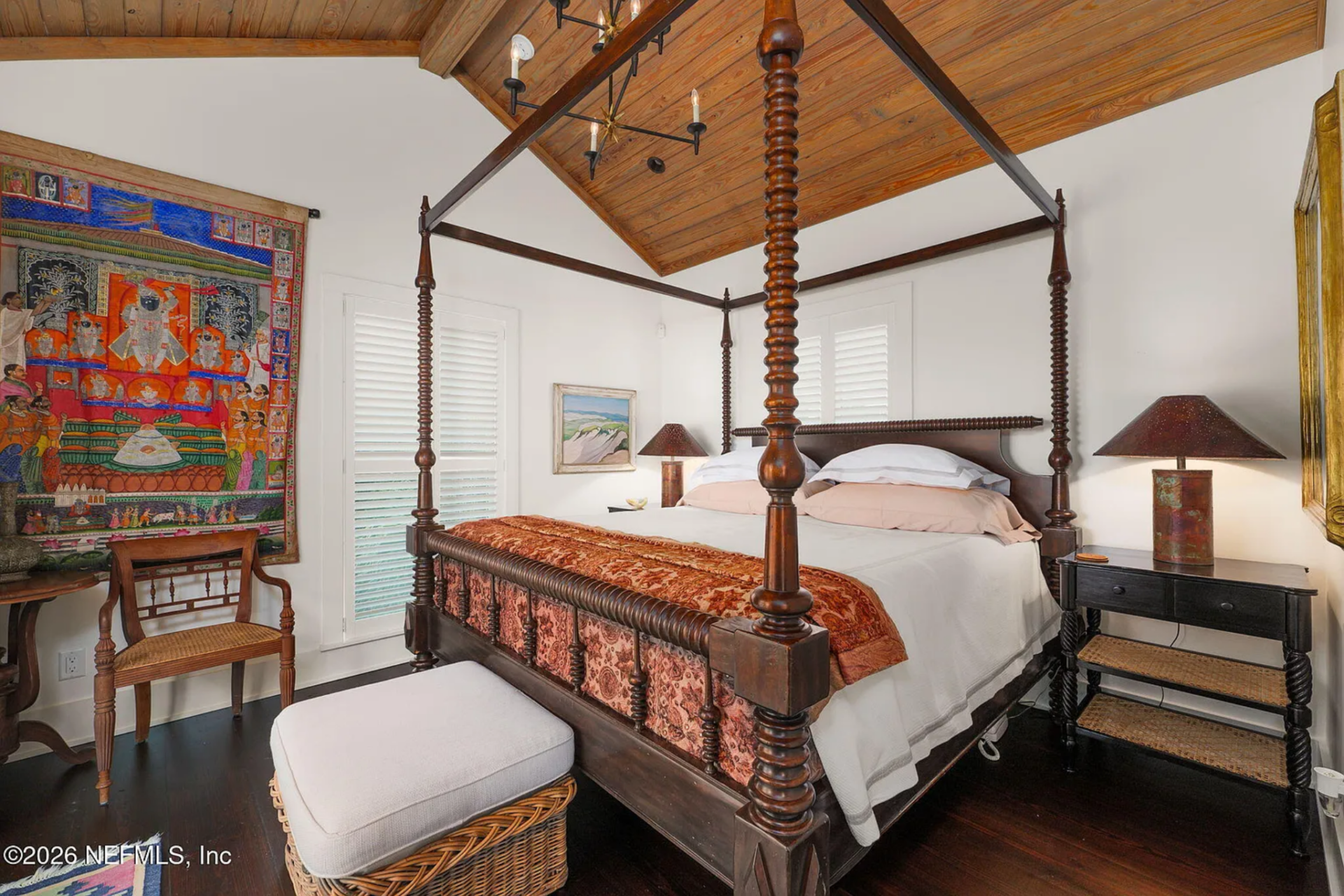 Bedroom with a layered, collected aesthetic, centered around a four-poster canopy bed with turned wood posts and a patterned textile draped across the foot.