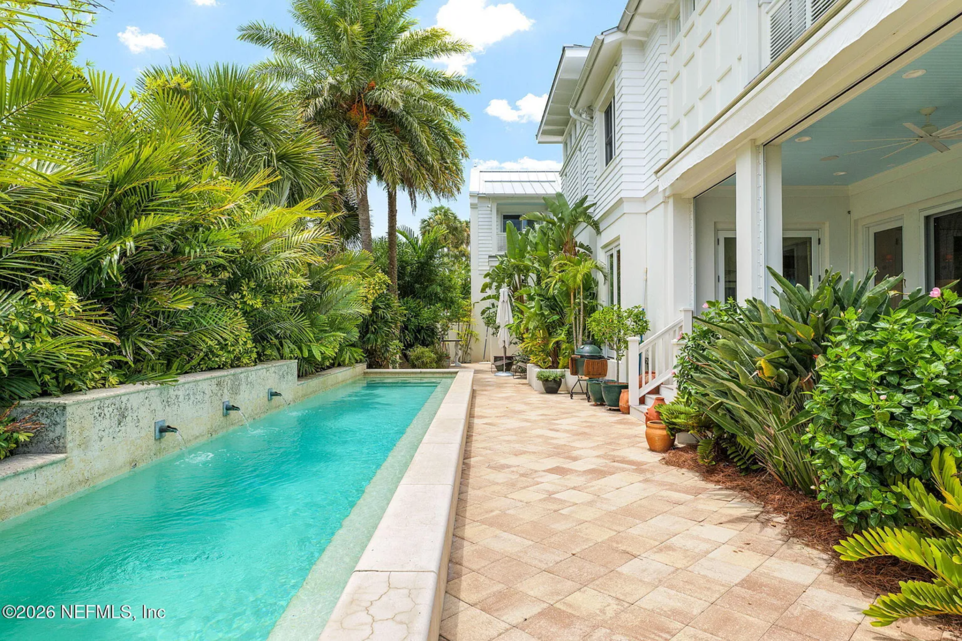 Running parallel to the house, the heated saltwater lap pool is designed with clean lines and a raised wall featuring water spouts that spill into the narrow basin.