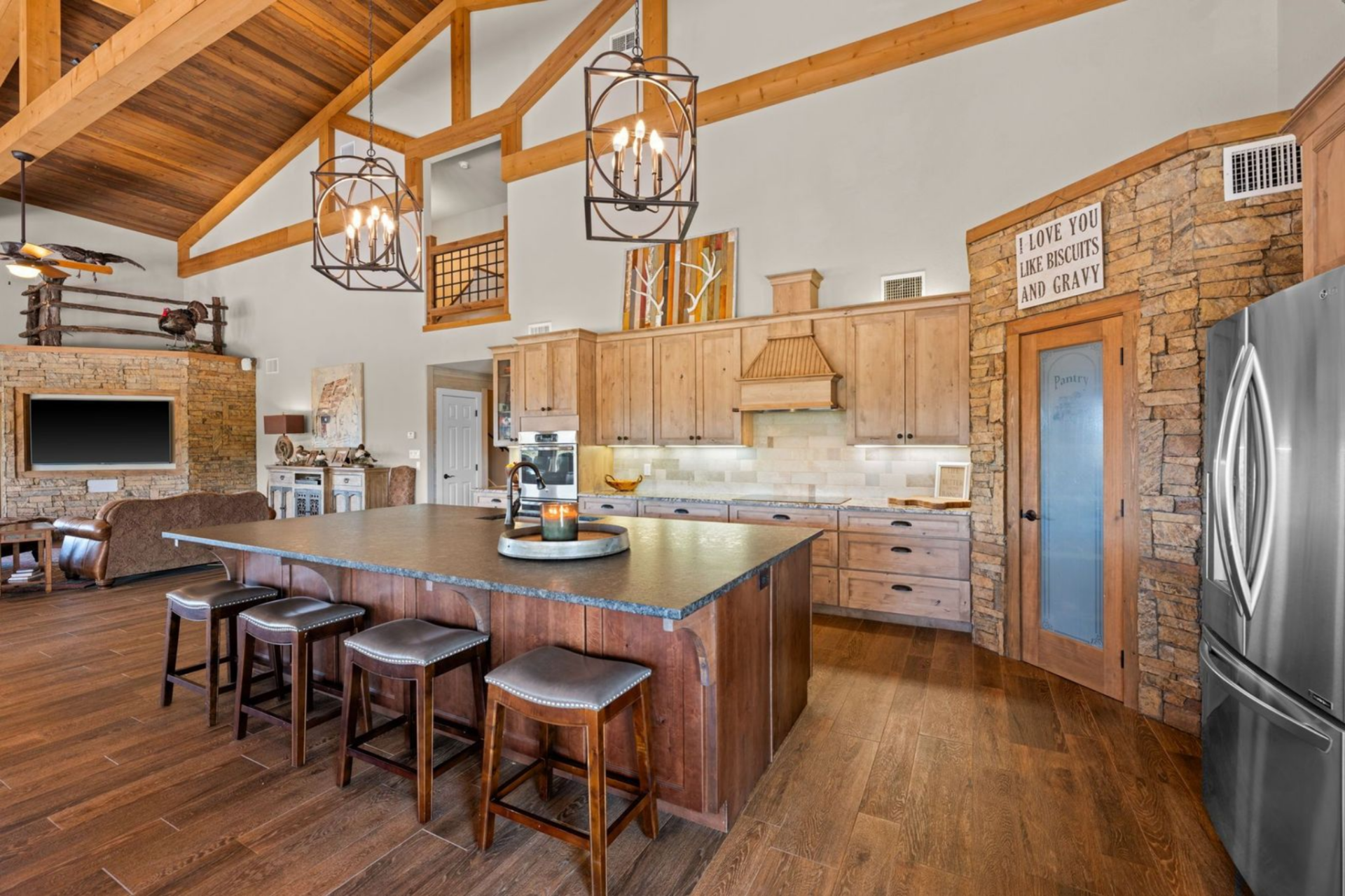 Custom wood cabinetry stretches to the ceiling, paired with granite counters and a neutral tile backsplash that keeps the space warm and cohesive. 
